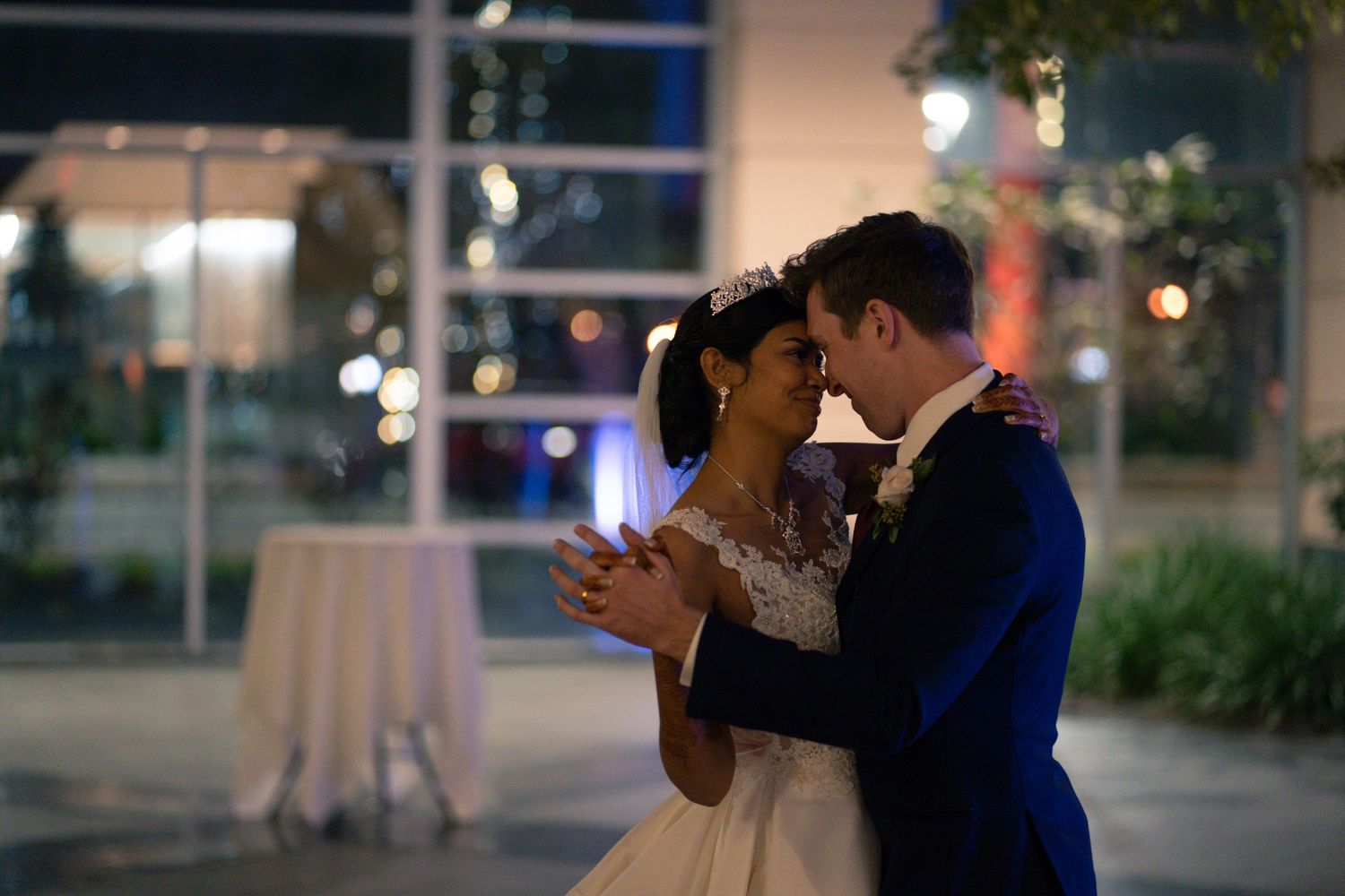 Romantic evening dance between newlyweds with soft lighting and garden backdrop.
