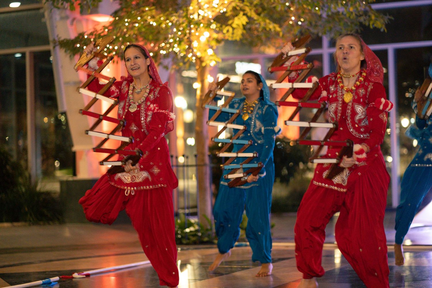 Performers in matching red and blue outfits dancing at a wedding reception.