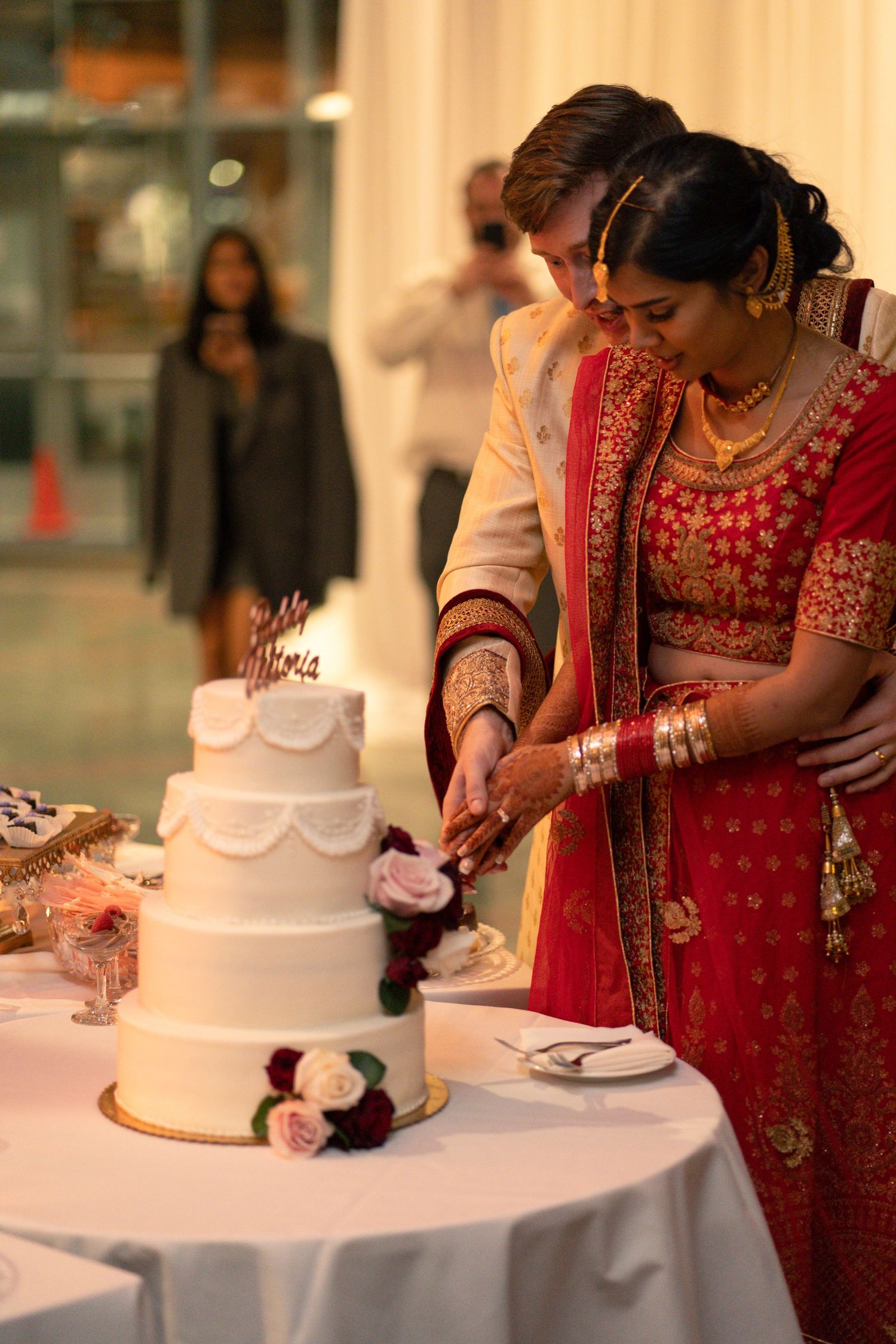 Traditional cake cutting ceremony with couple in formal Indian wedding attire.