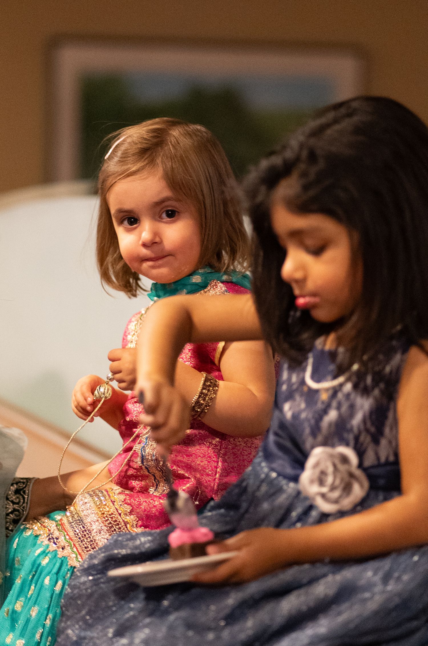 Two young children in formal attire sitting together at a wedding celebration.