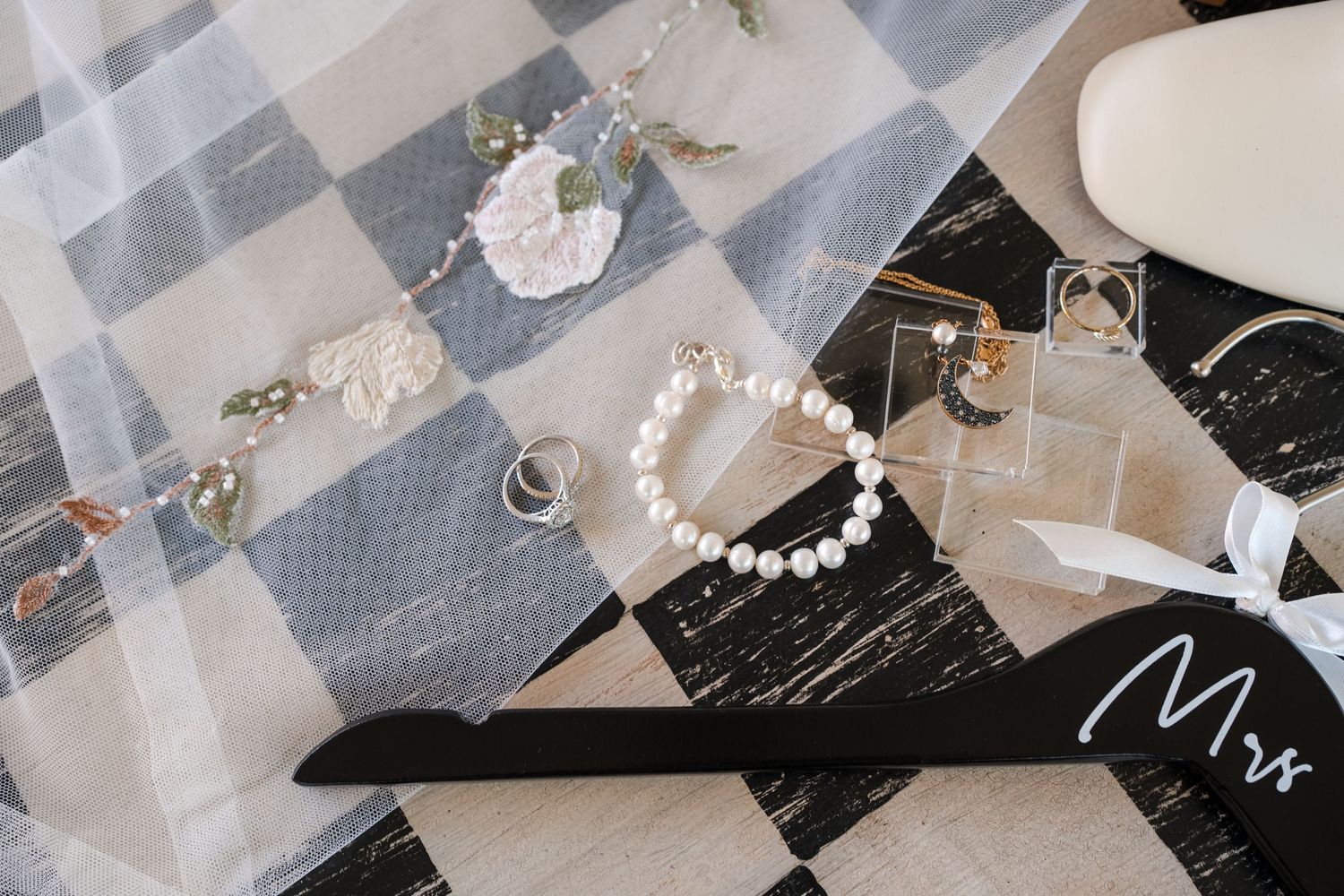 Wedding accessories including jewelry and pearls arranged on marble surface.