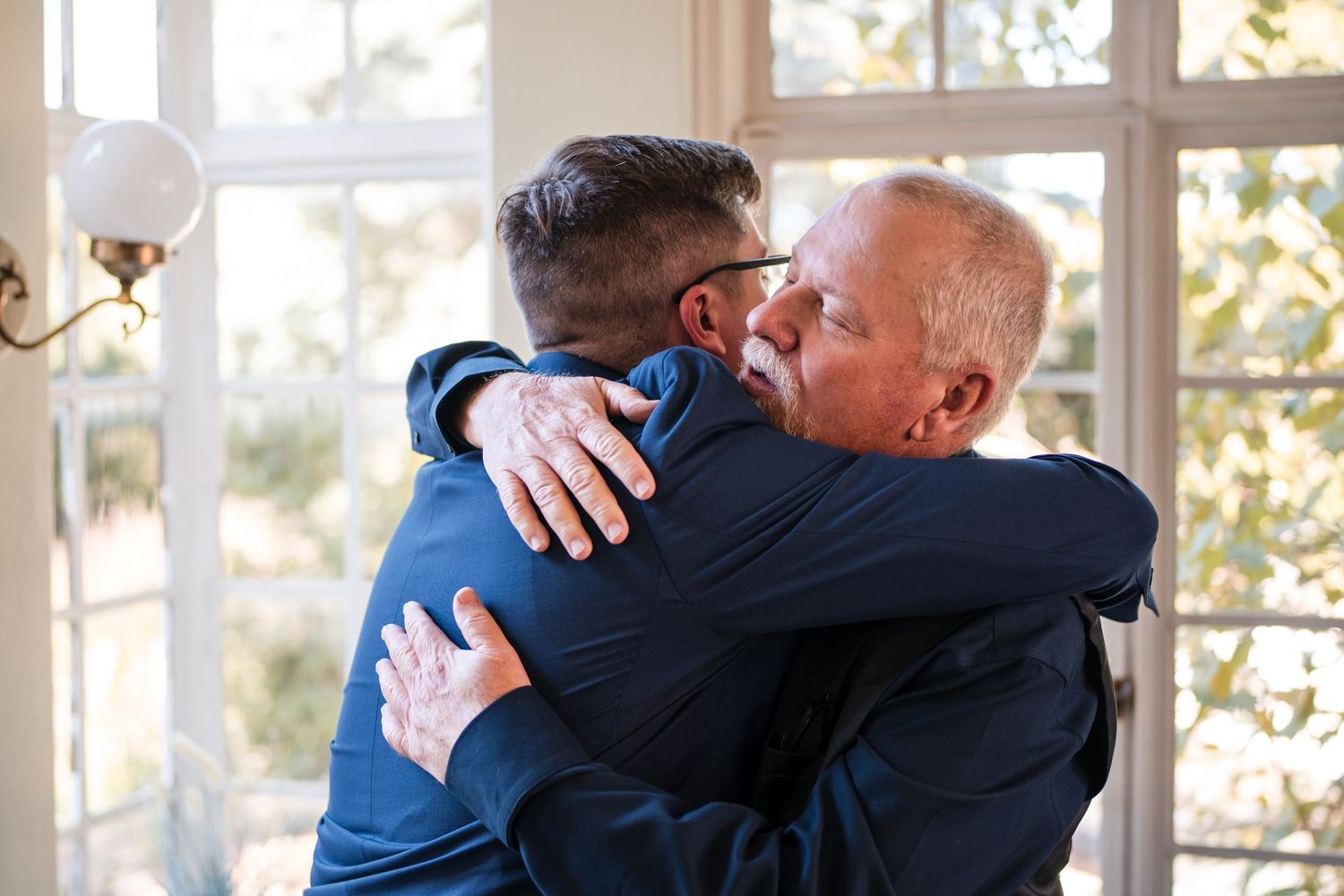 Emotional embrace shared in a sun-lit room with windows.