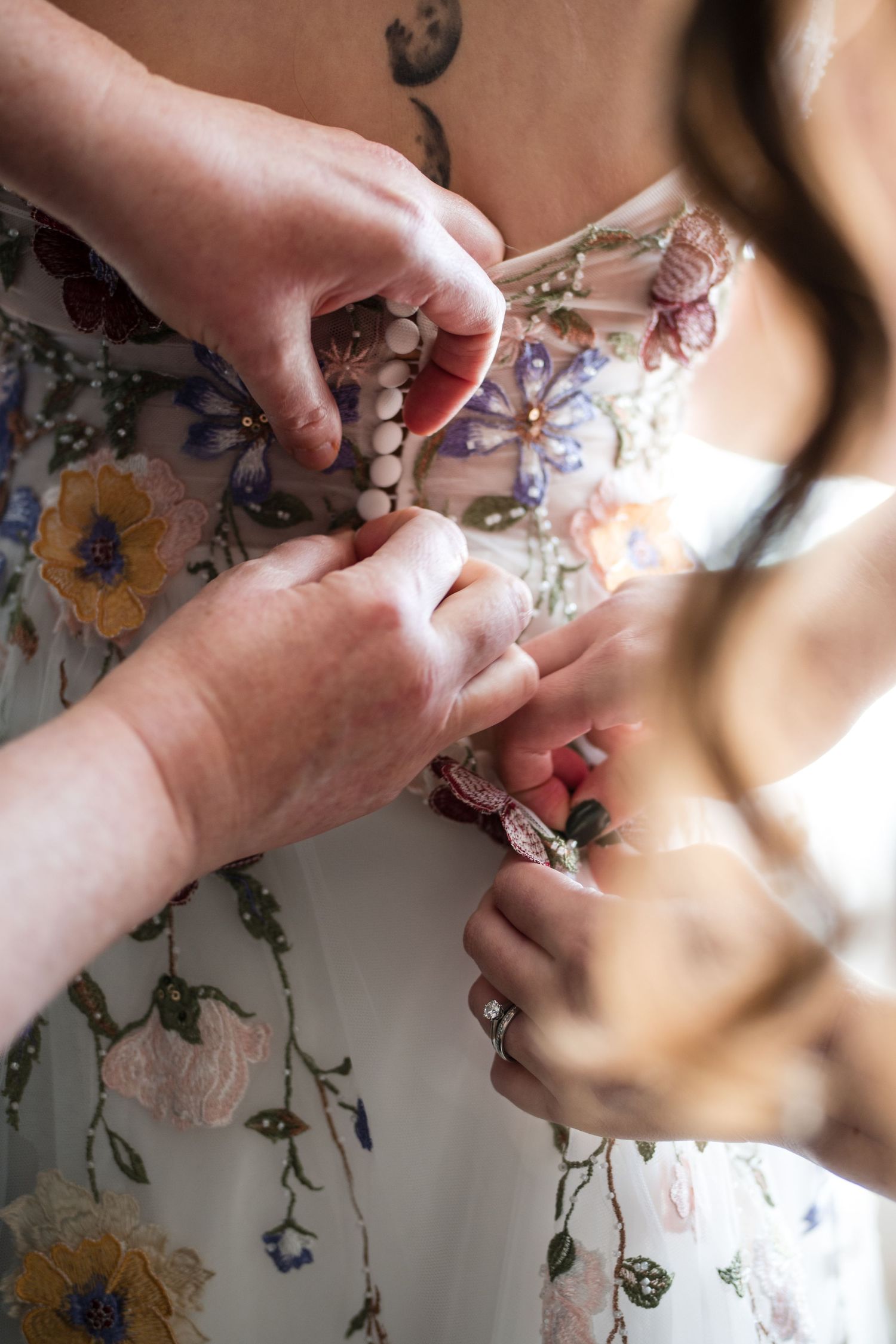 Hands adjusting a floral dress with delicate details in natural lighting.