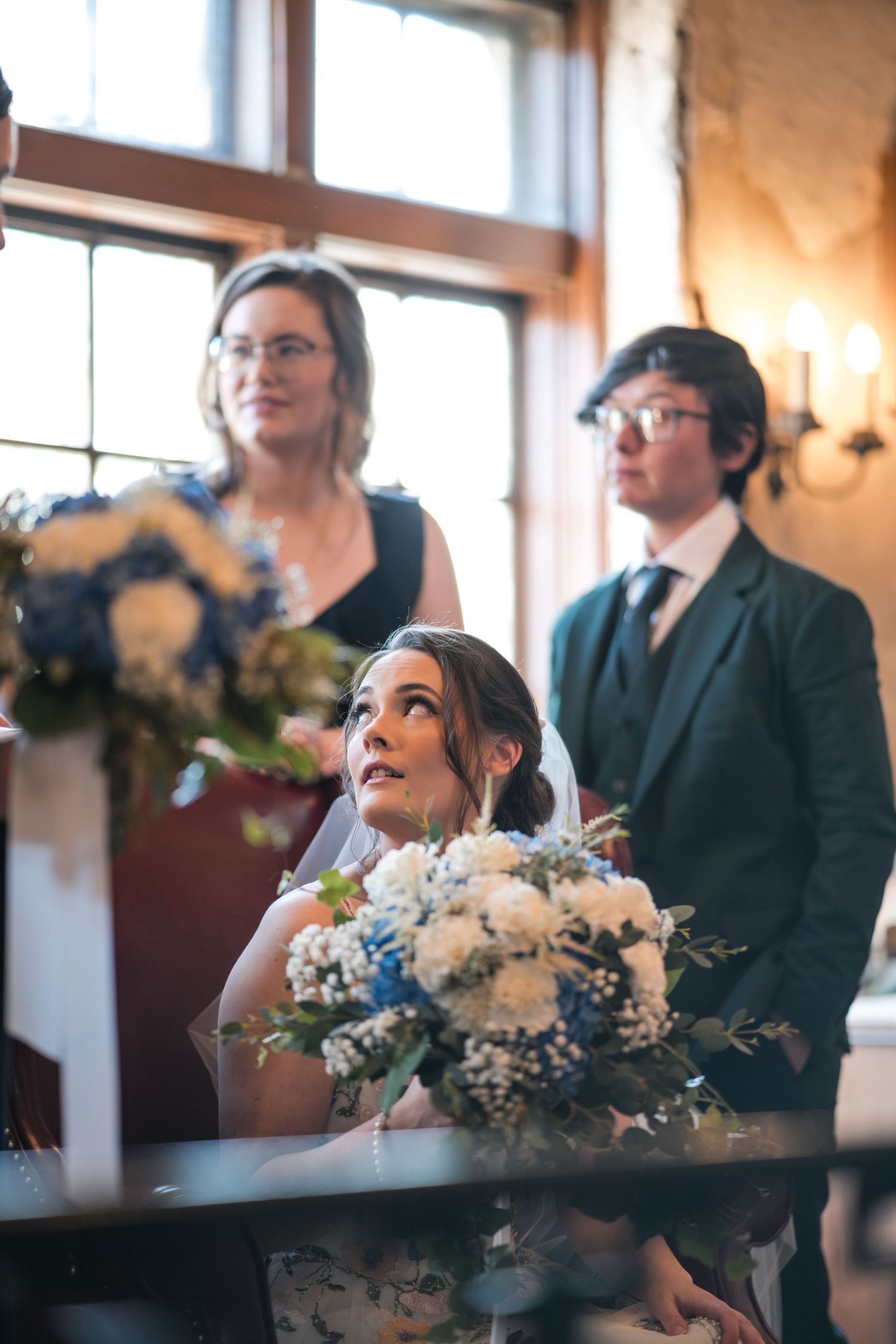 A wedding ceremony scene with blue and white floral arrangements in an elegant indoor setting.