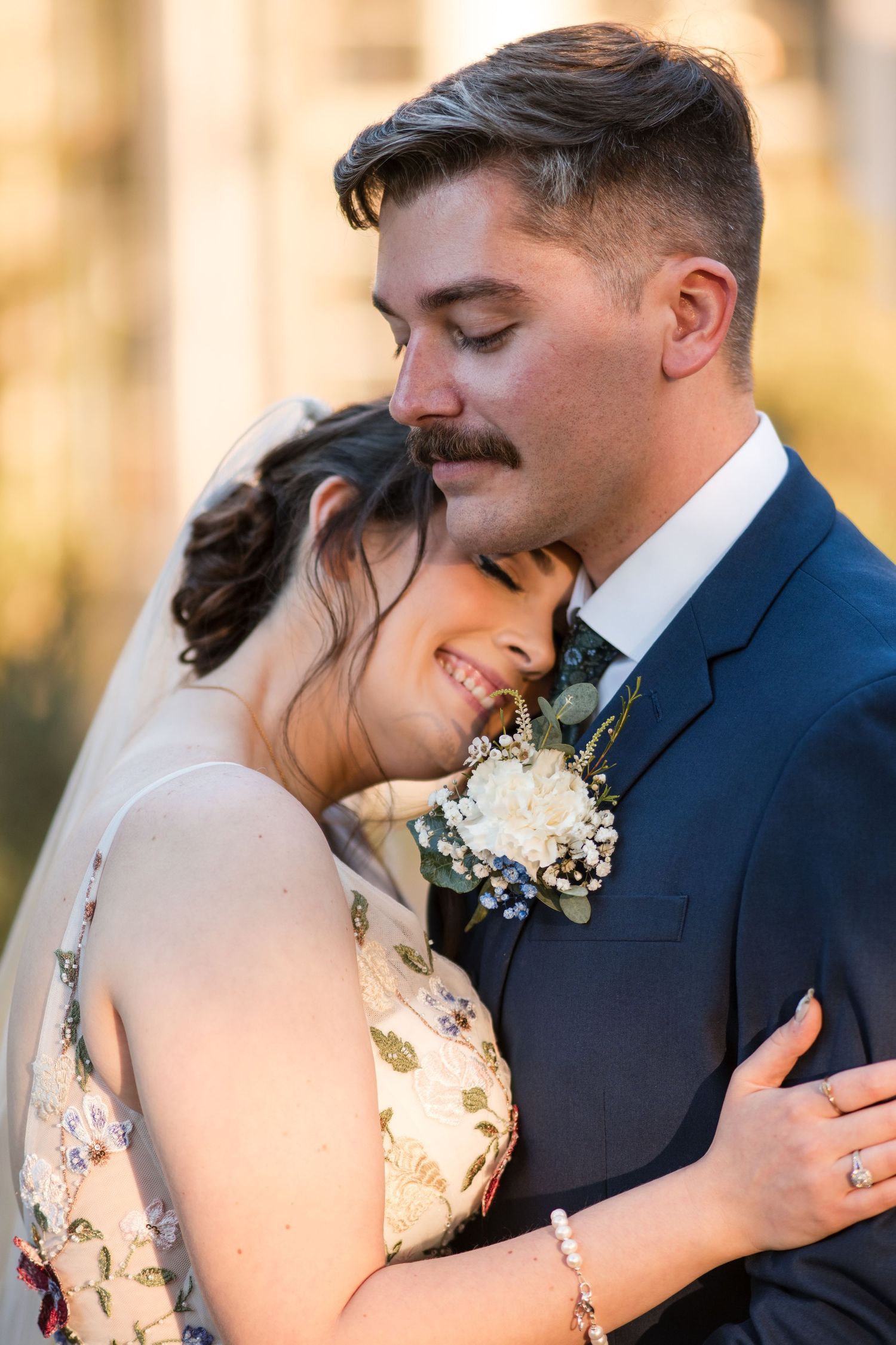 Tender embrace captured during golden hour wedding photography with delicate floral details.
