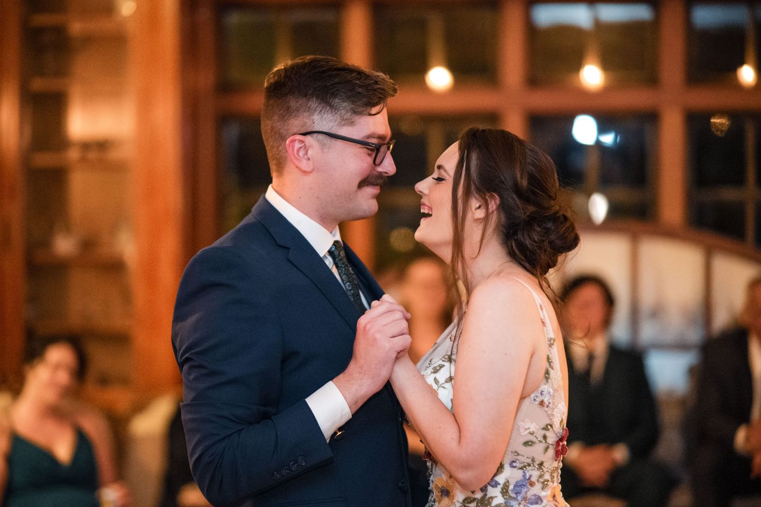 Newlyweds share their first dance in an elegantly lit reception venue.