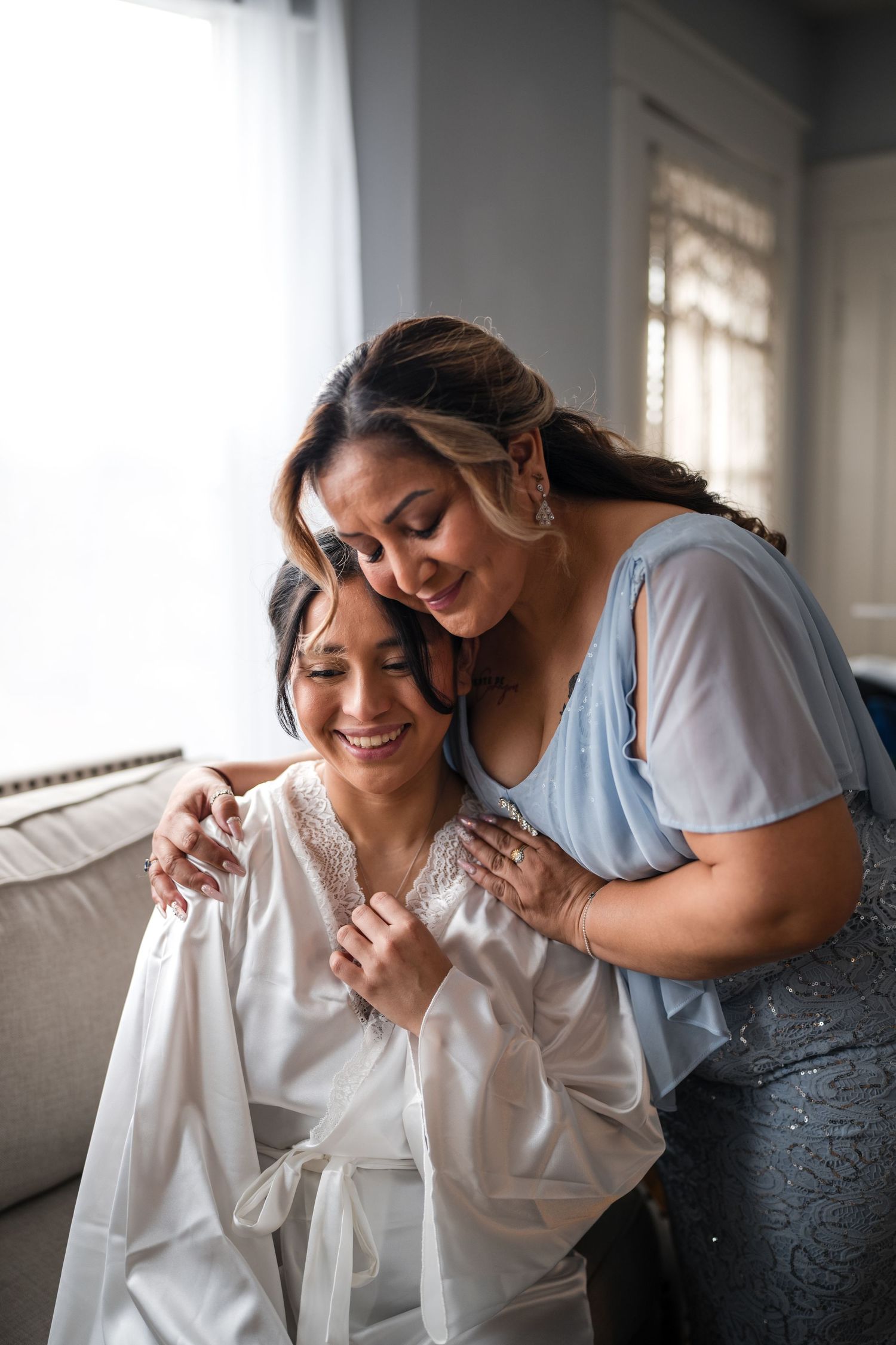 Two friends share a tender moment of joy while embracing in a naturally lit room.