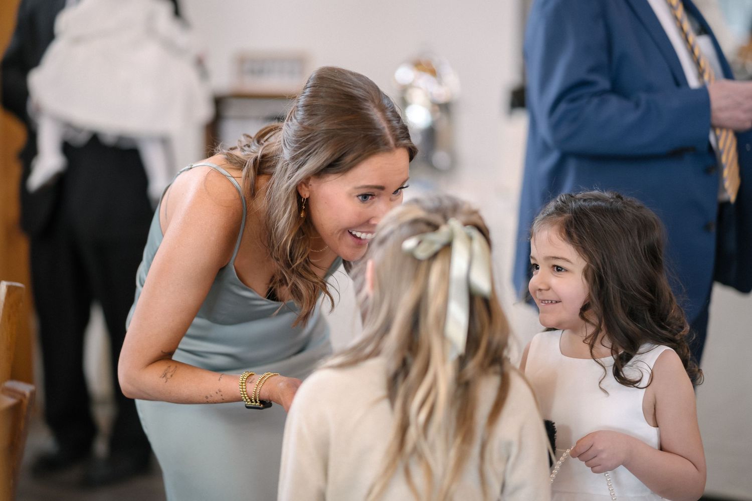 Three people share a joyful moment during a social gathering, laughing and interacting with genuine emotion.