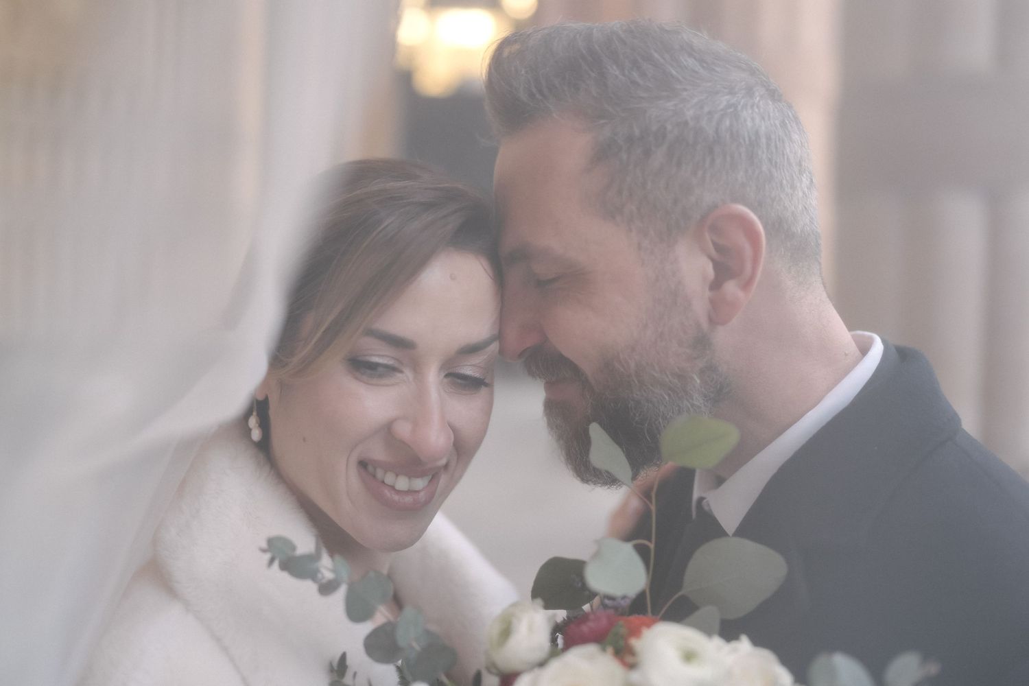 A wedding couple sharing an intimate moment with winter fur stoles and roses in soft romantic lighting. Buffalo City Hall