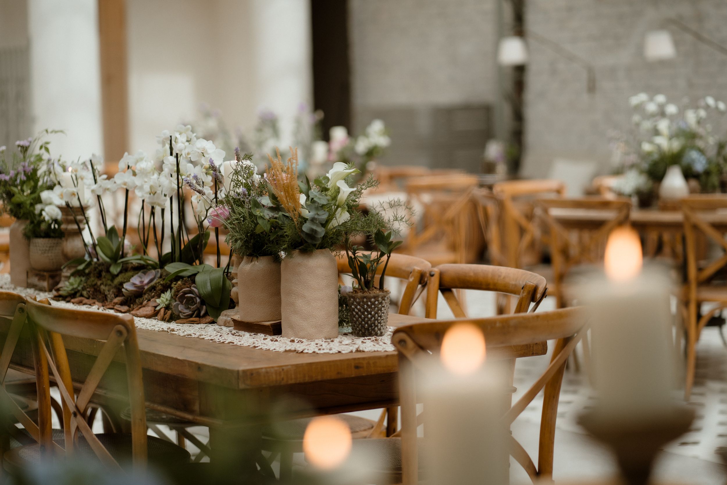Rustic wedding table setting with candles and natural floral centerpieces.