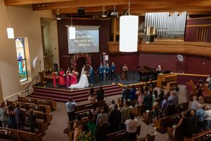 Overhead view of a church wedding ceremony with guests seated in pews and couple at floral arch altar.