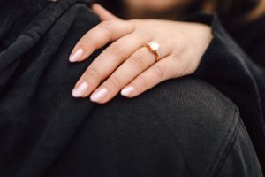 Close-up of woman's hand wearing a delicate rose gold engagement ring.