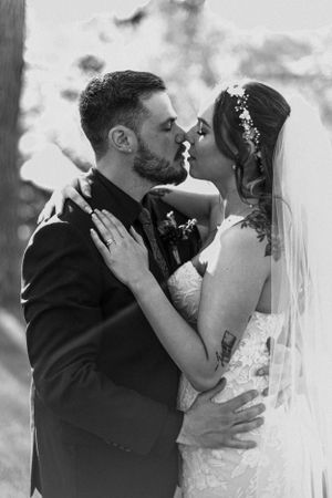 Black and white photo of bride and groom sharing a romantic kiss on wedding day.