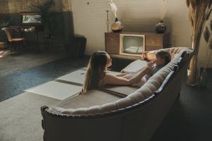 A couple relaxing together on a leather sofa in a cozy, vintage-styled living room.