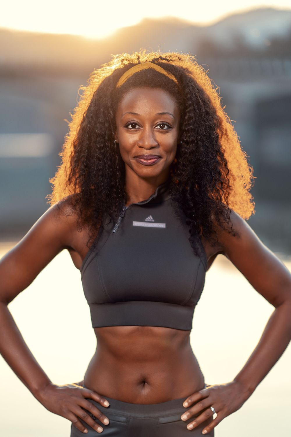 Beverley Knight standing in front of a lake in Portugal with the sun behind her