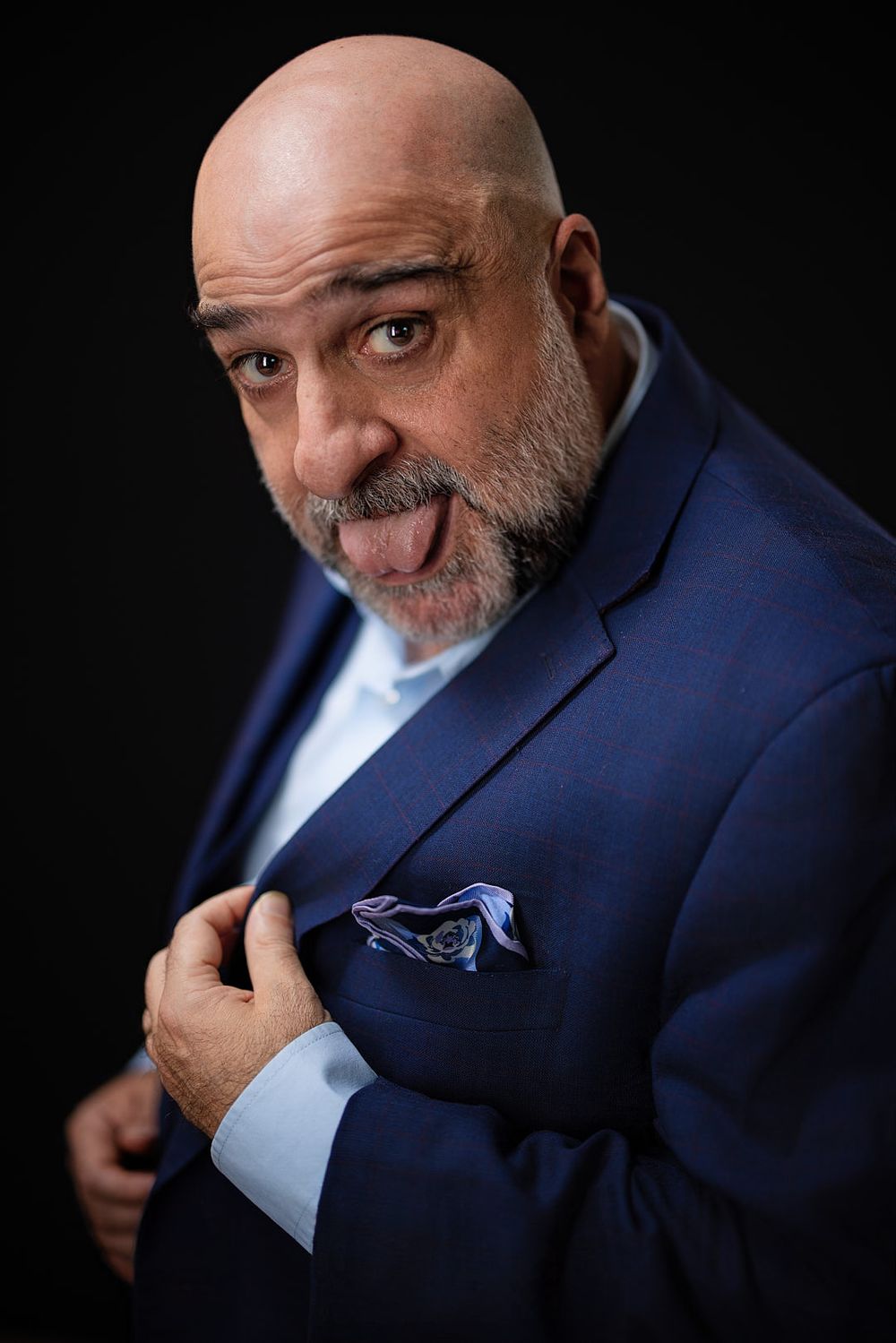 Omid Djalili leaning towards the camera threatening to lick his pocket handkerchief