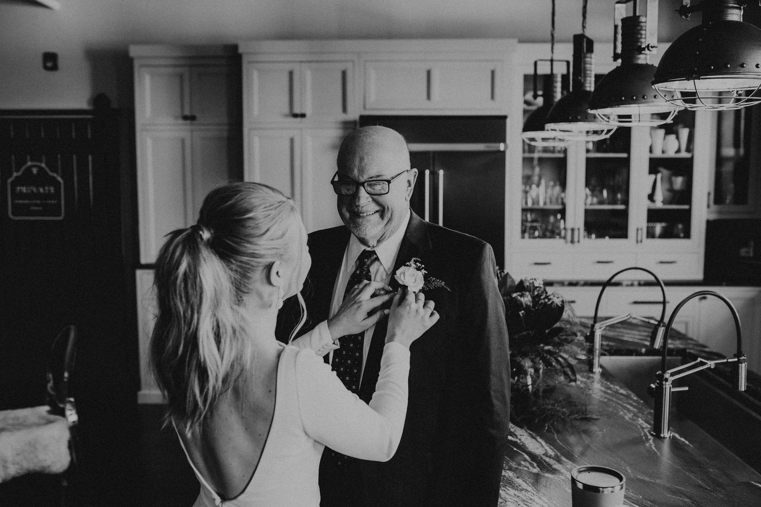 Black and white candid moment captured during a dance on a hardwood floor in what appears to be a home setting.