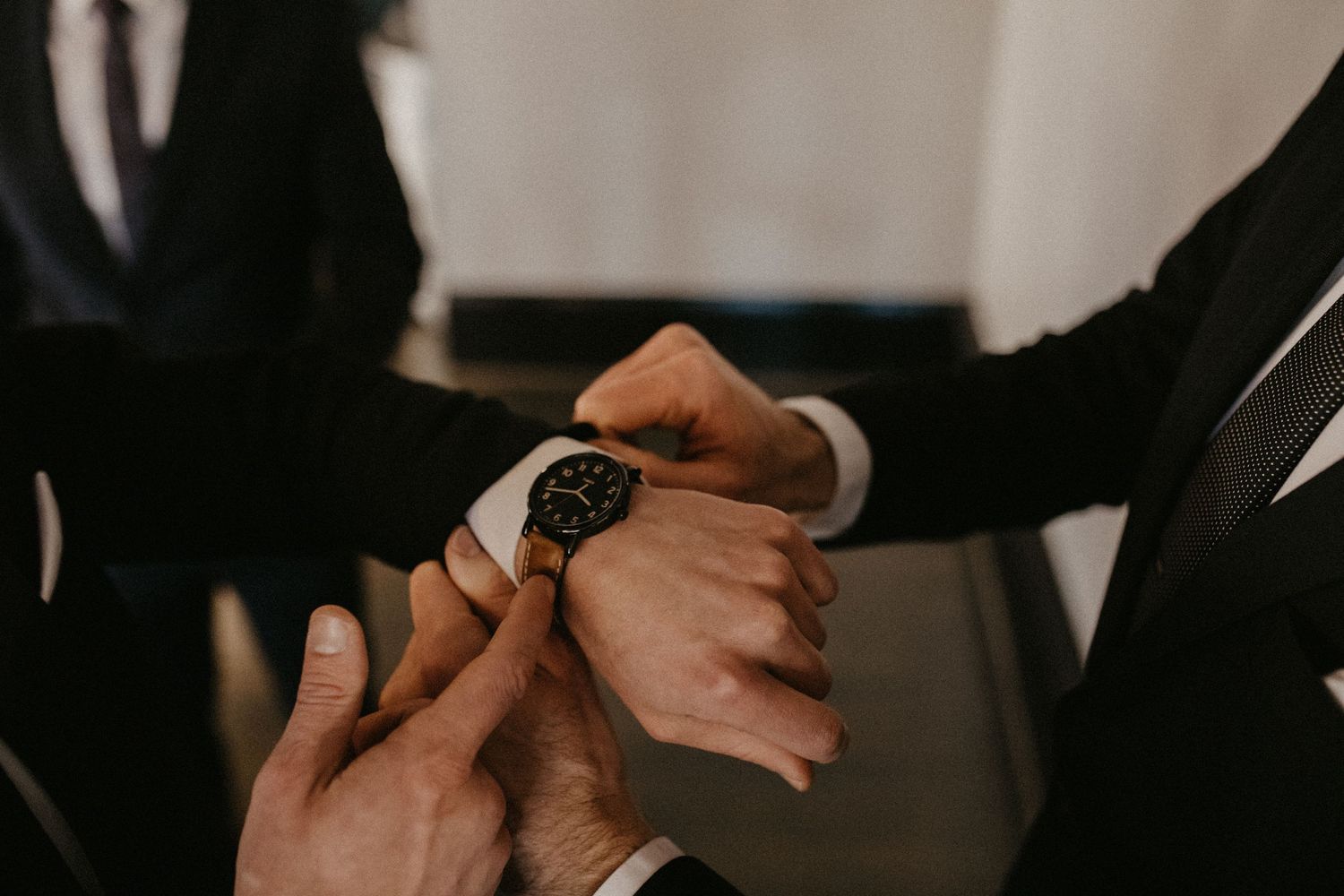 Someone checks their wristwatch while dressed in formal black attire during a special occasion.