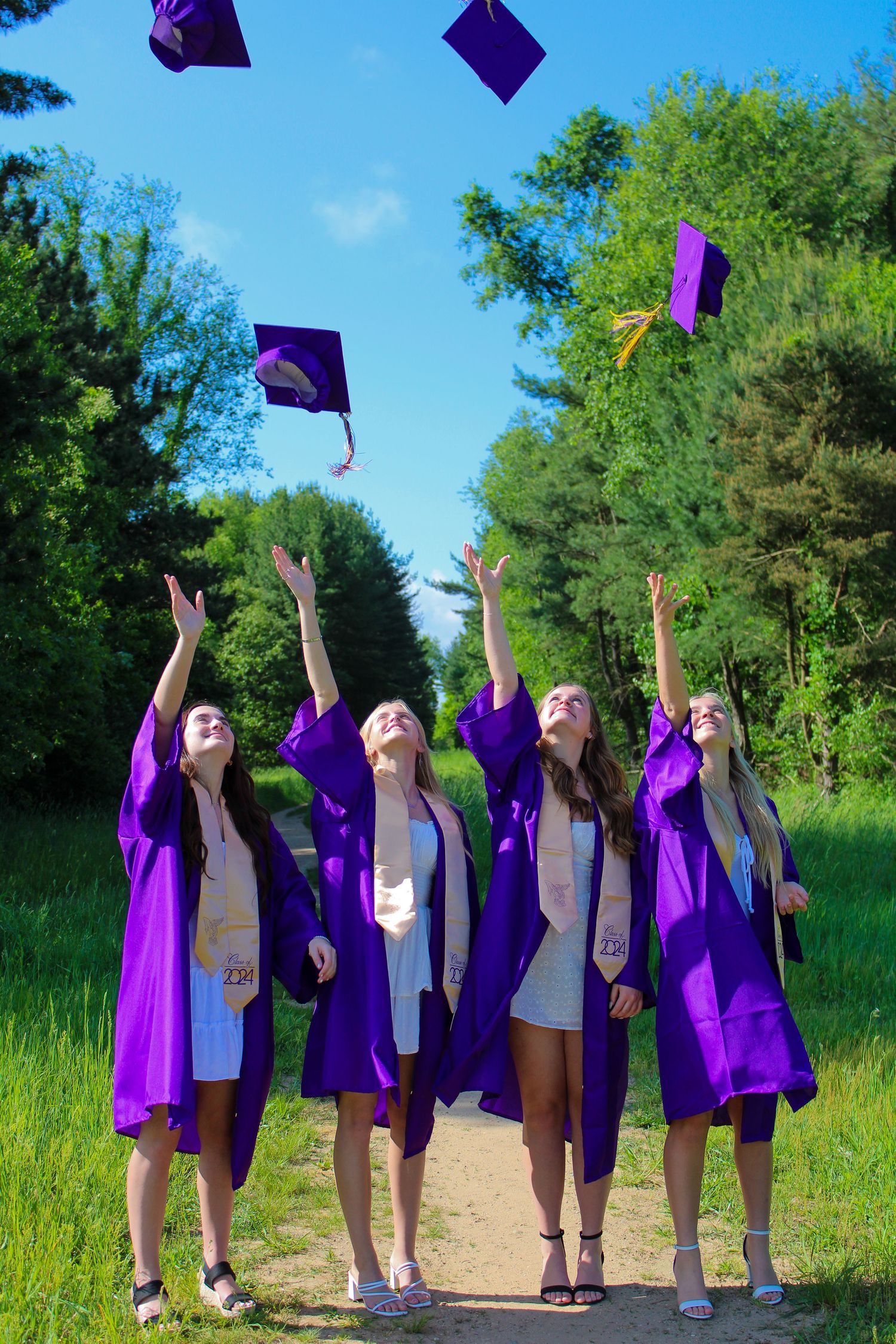 Graduates tossing purple caps in the air during outdoor celebration.