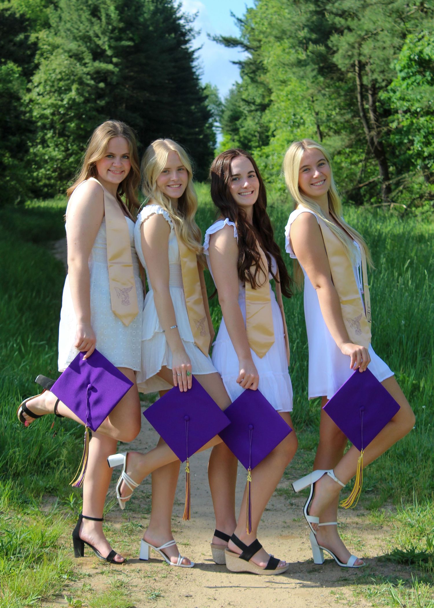 Creative graduation photo series showing purple caps being tossed in a natural outdoor setting.