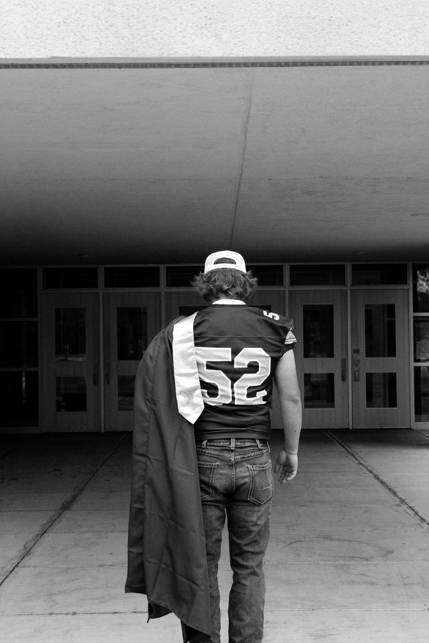Black and white photo sequence showing someone walking away wearing graduation attire and sports jersey.