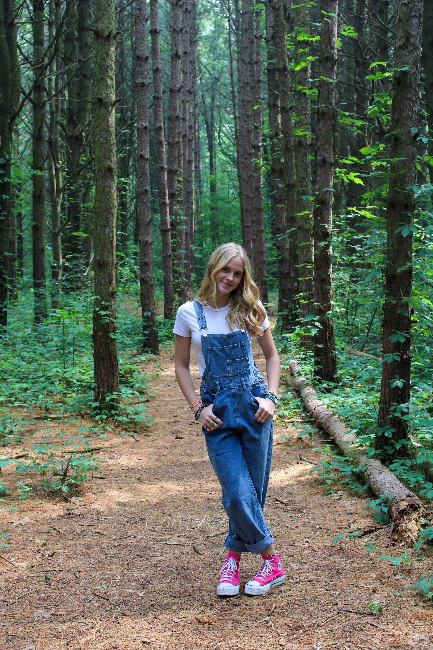 Series of photos showing someone in overalls and pink shoes walking through a pine forest.