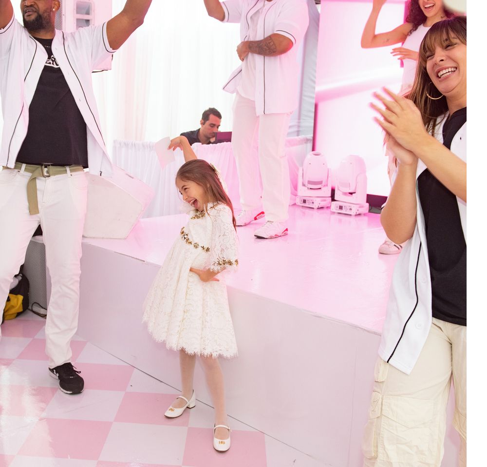 Young guests in white dresses enjoy dancing at a pink-themed party with LED lighting and entertainment.