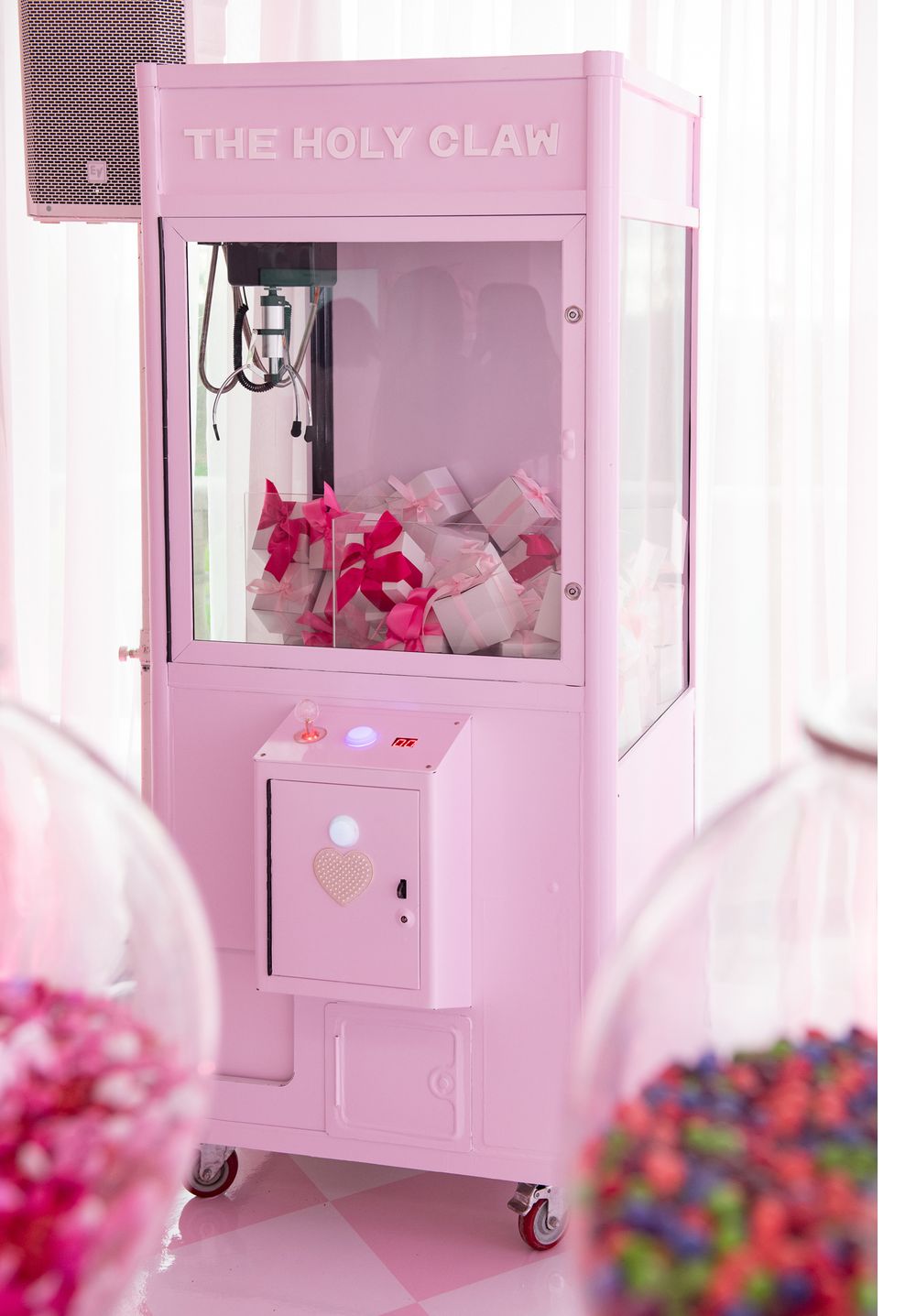 Pink claw machine arcade game titled 'The Holy Claw' filled with plush toys.