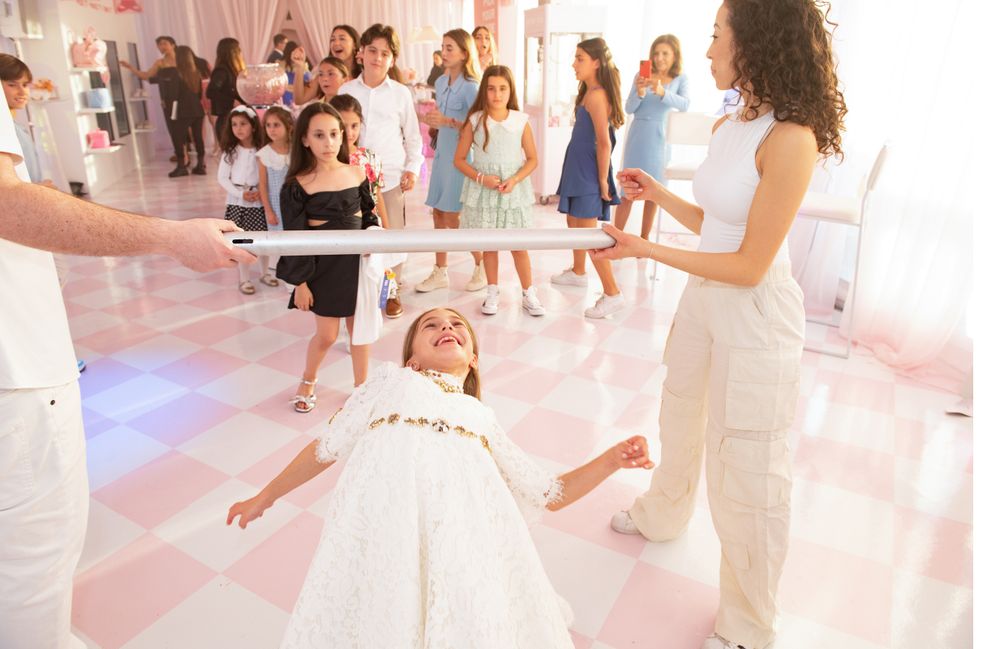 Guests twirling and dancing on a pink and white checkered floor at a celebration.