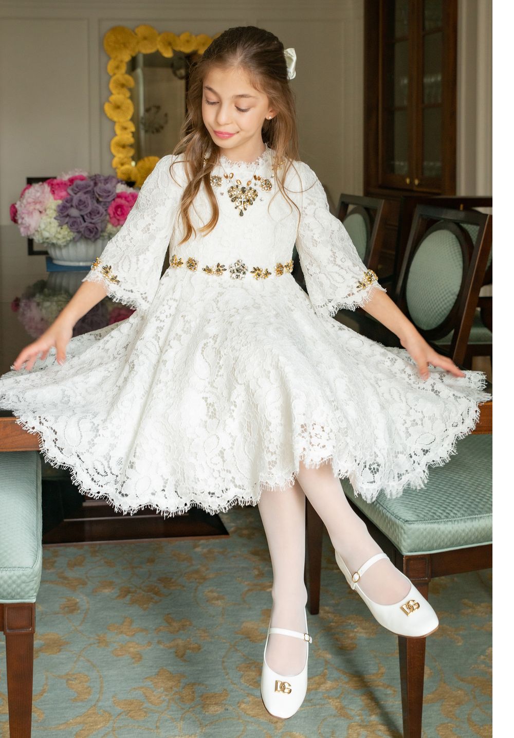 White lace dress with gold accents twirls gracefully in elegant interior setting.