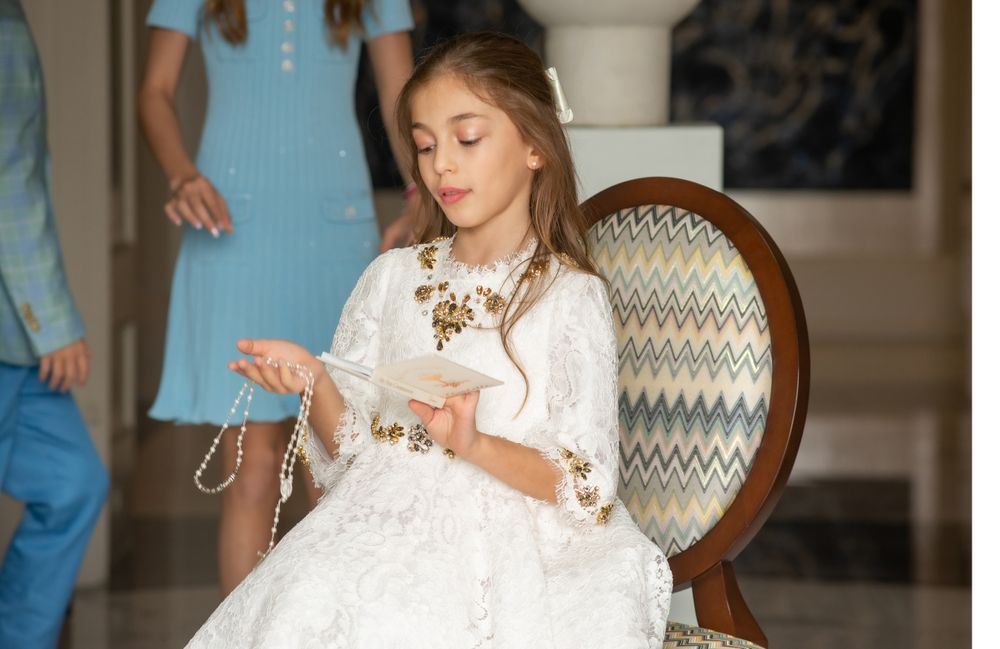 A decorative scene featuring a white lace dress with gold embellishments and an ornate chair.