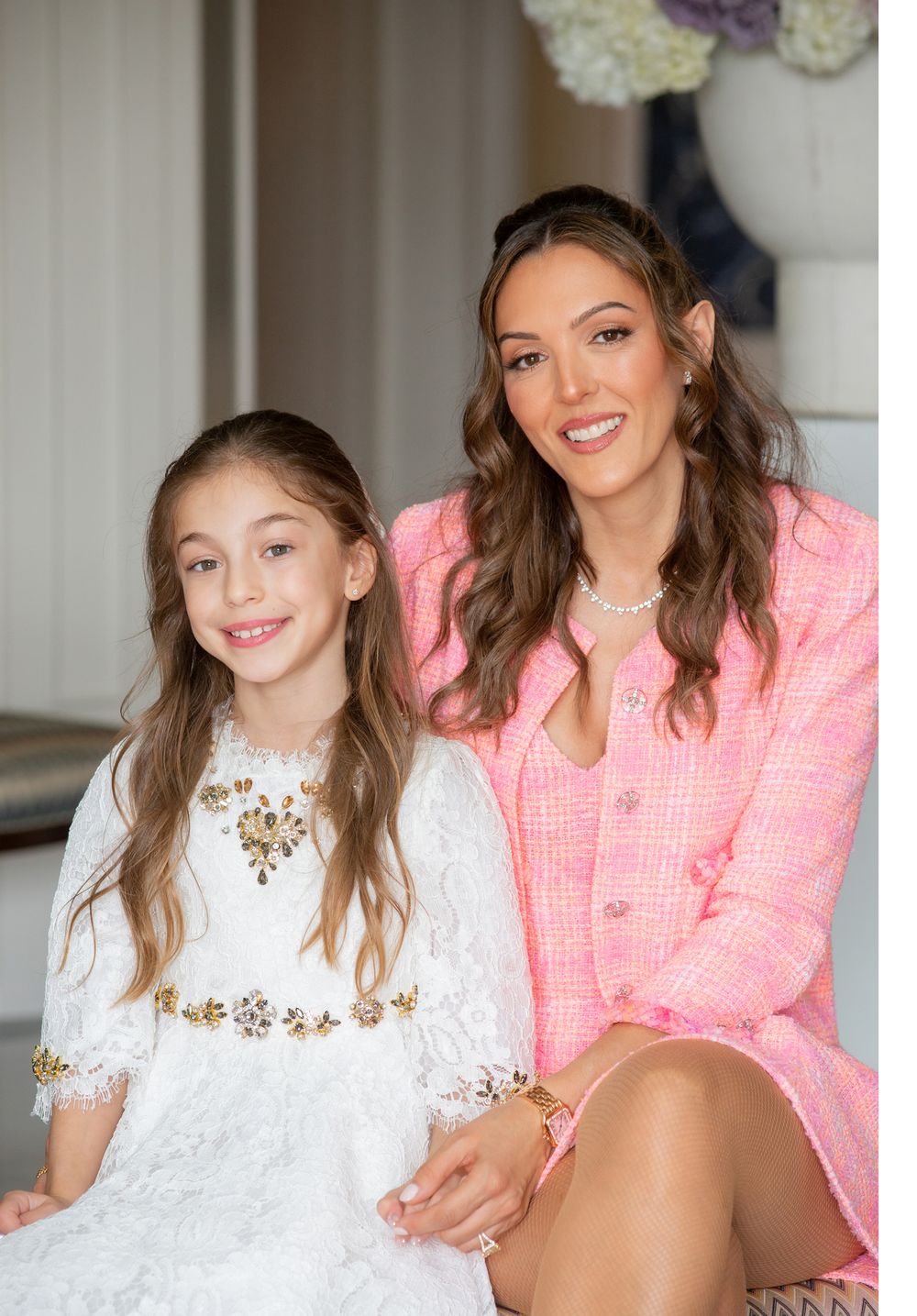 A heartwarming portrait featuring a pink blazer and white lace dress against an elegant backdrop.