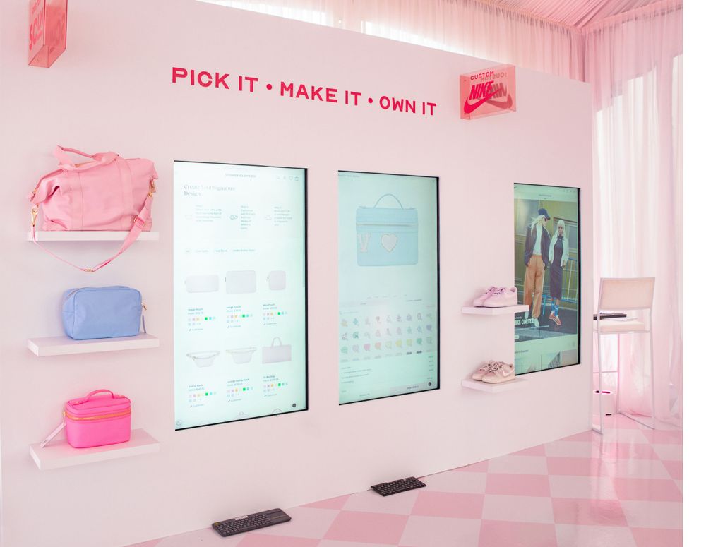 Pink interior space with digital displays and neon signage saying 'Pick it, Make it, Own it'.