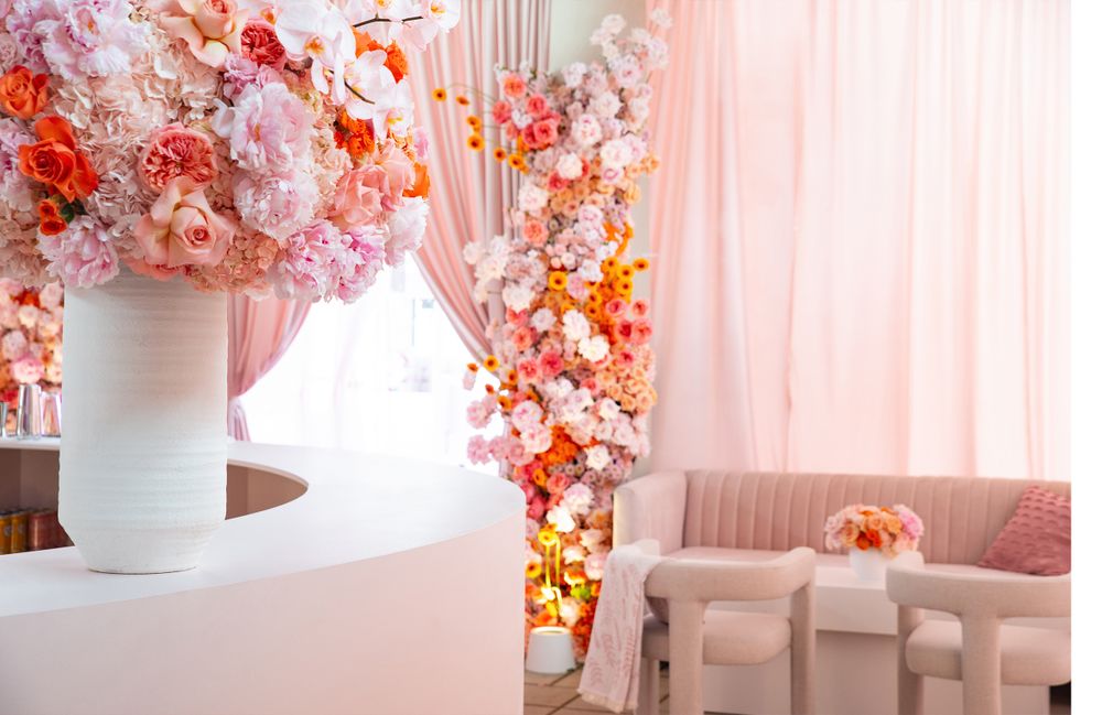 Pink and coral floral decor installation with elegant white furniture setting.