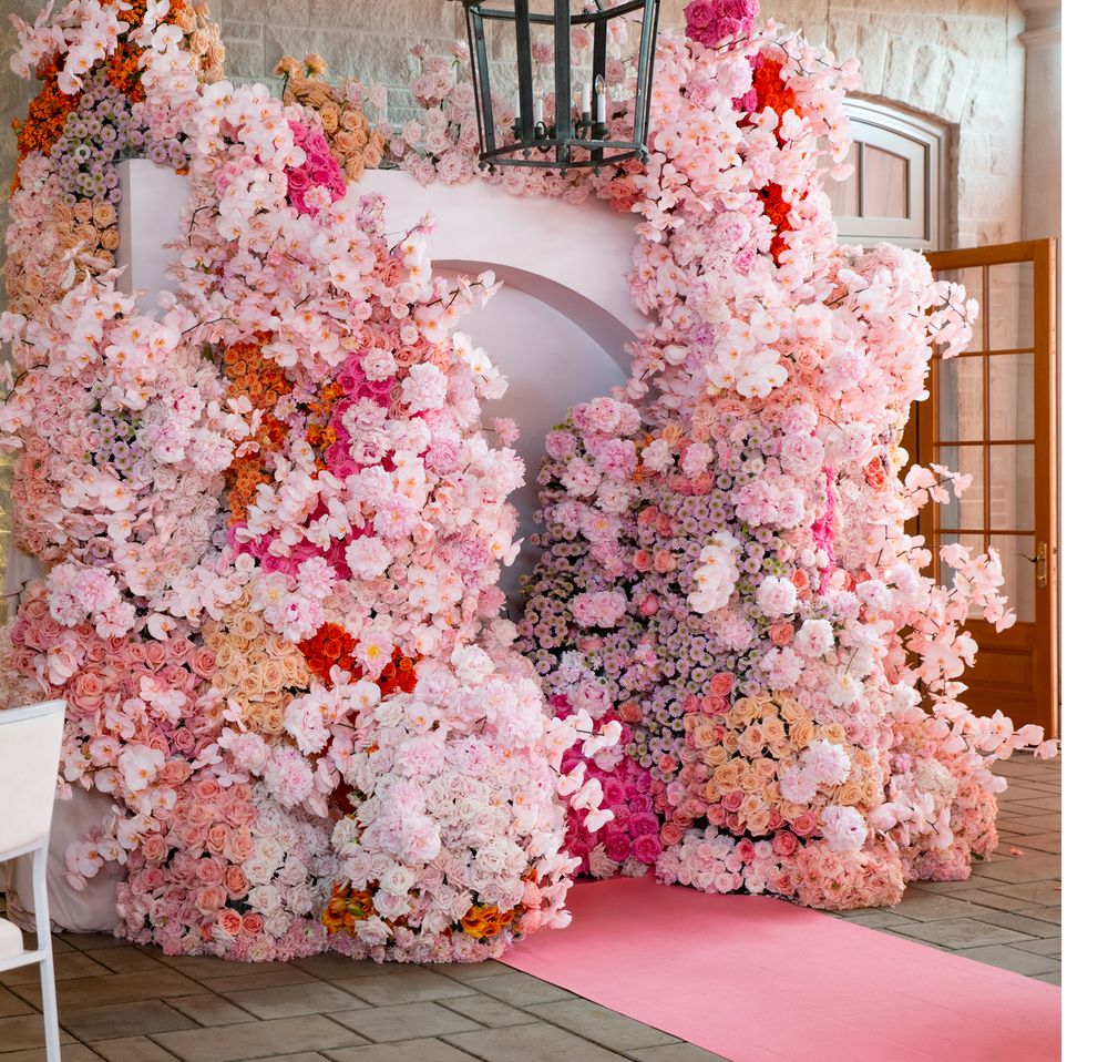 Romantic floral arch installation with pink blooms and lantern detail.