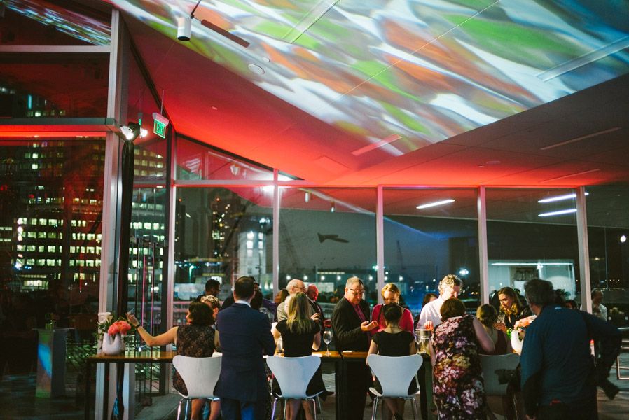 Colorful LED lights illuminate a modern event space with people mingling under dynamic ceiling projections.