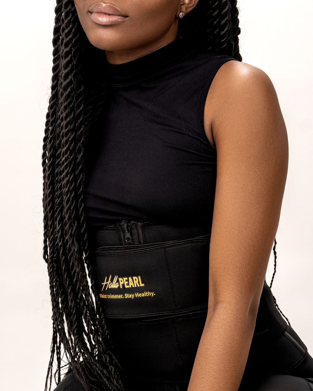 Model in black sleeveless top with long braids showing waist trainer.