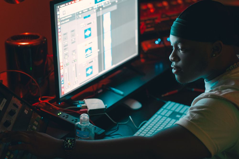 Person working at computer setup in dark room with red ambient lighting.