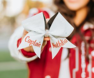 Close-up of a white and red cheerleading bow with 'Captain' text. Creative graduation photos in Patterson.