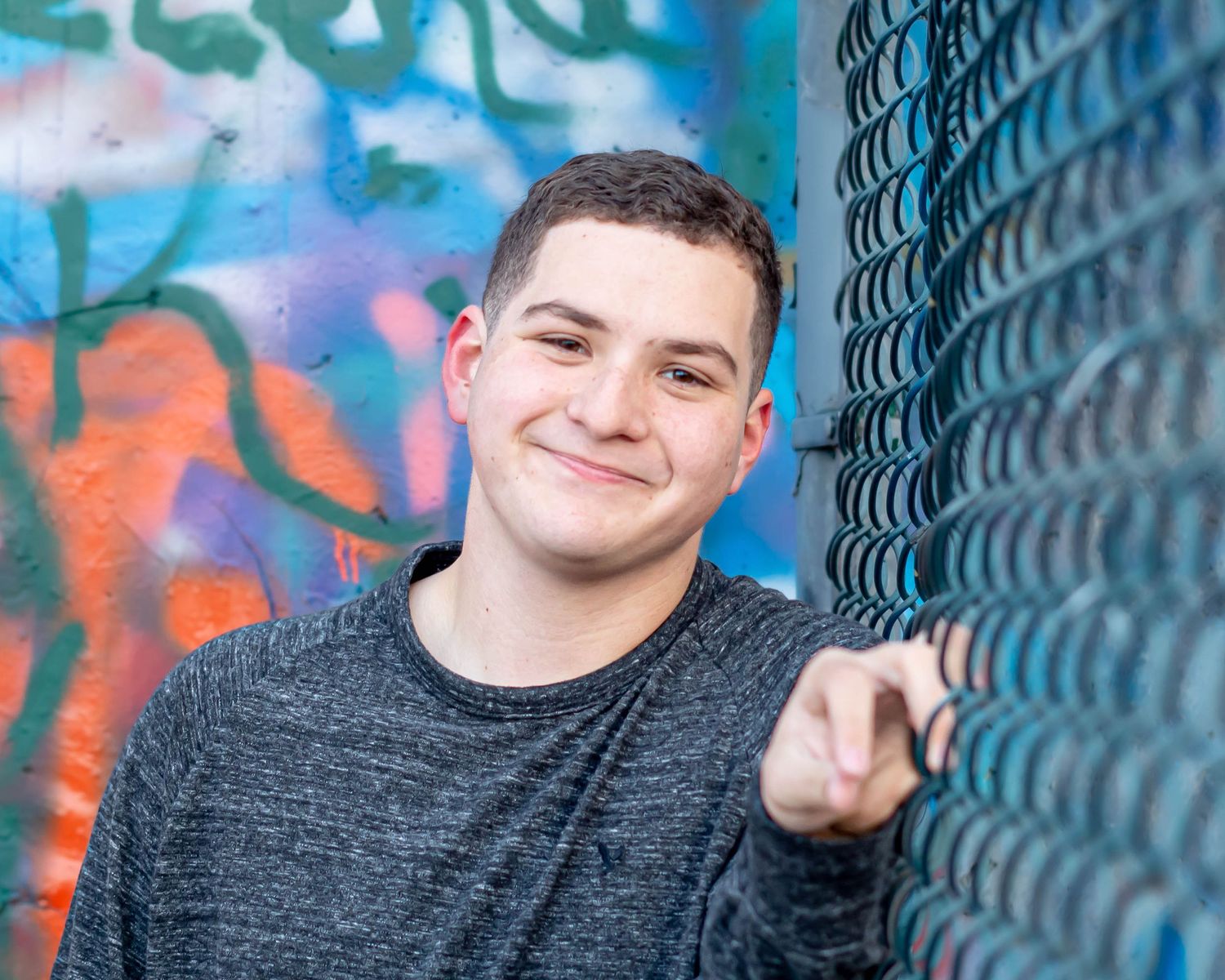 Colorful portrait session against chain link fence with vibrant background.