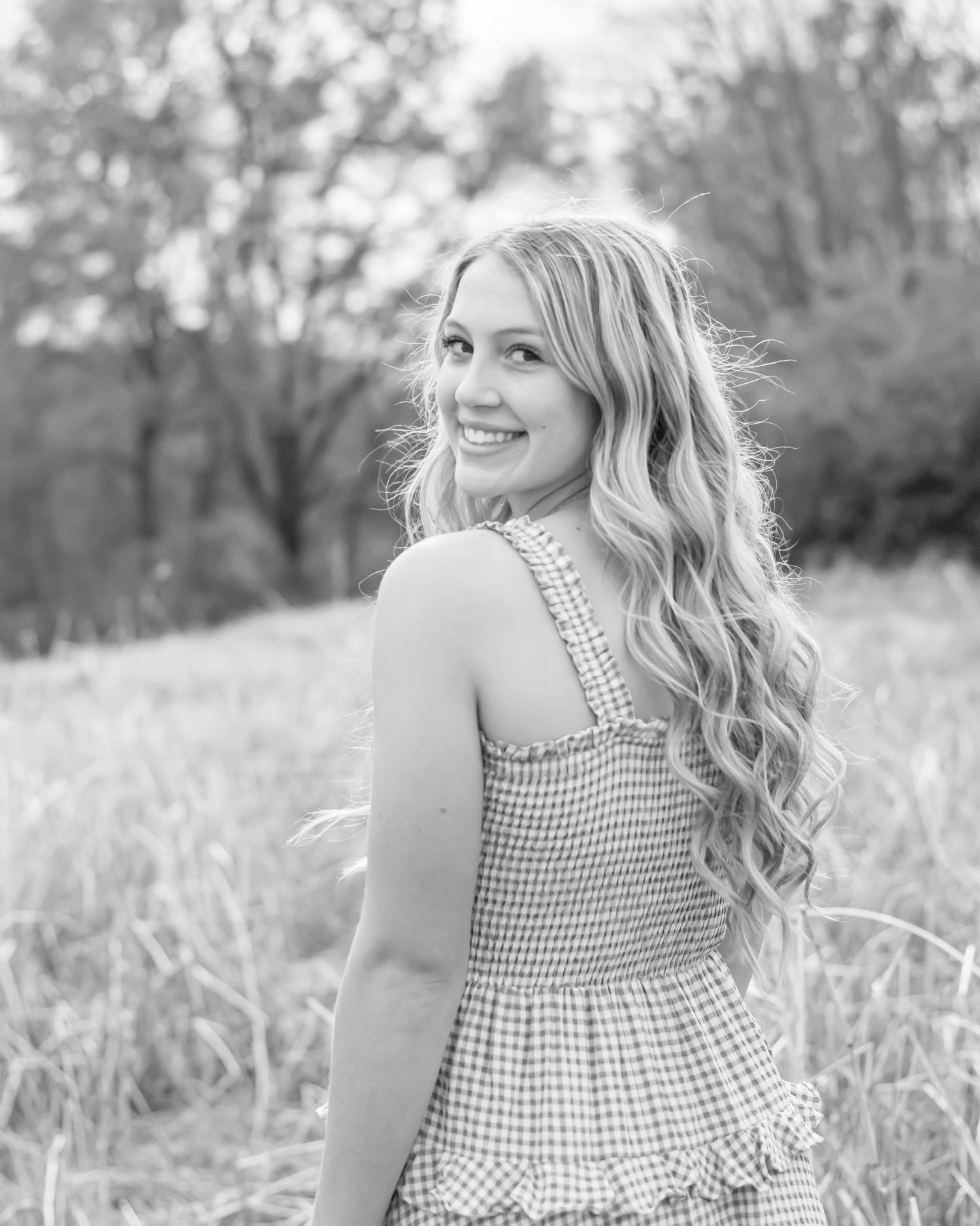 Black and white portrait session in tall grass field.