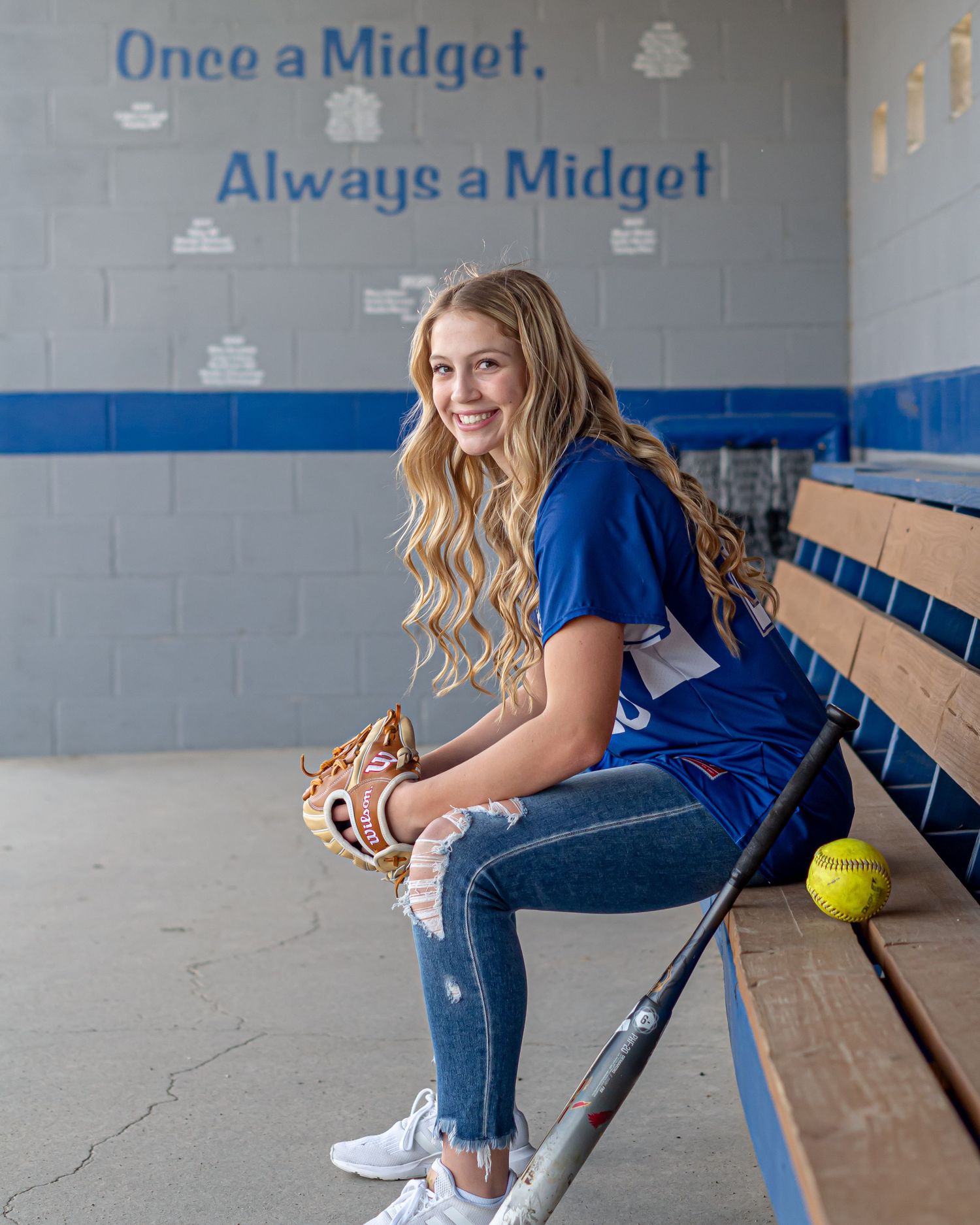 Athletic photo shoot on locker room bench with softball equipment.