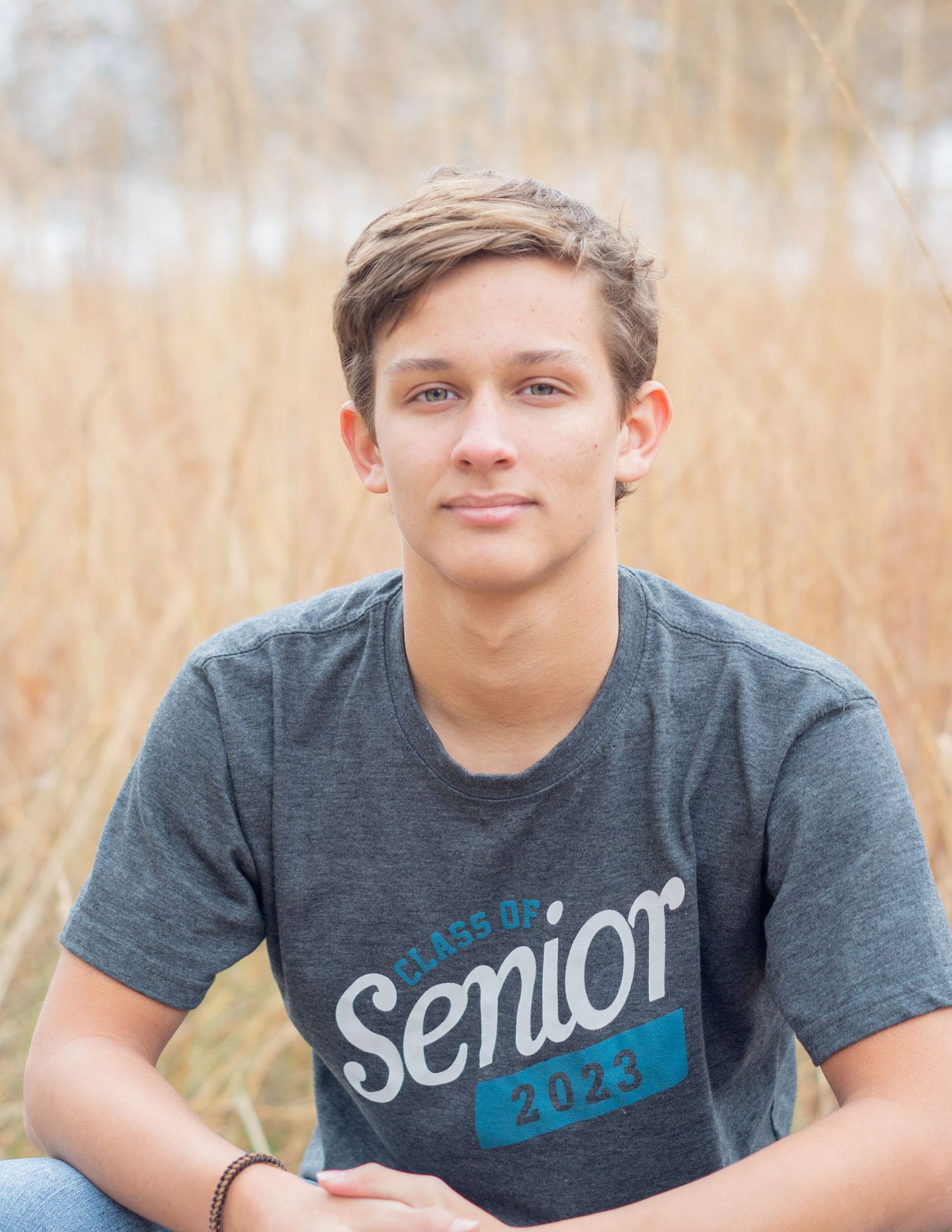 Senior portrait session in field with student wearing grey t-shirt.