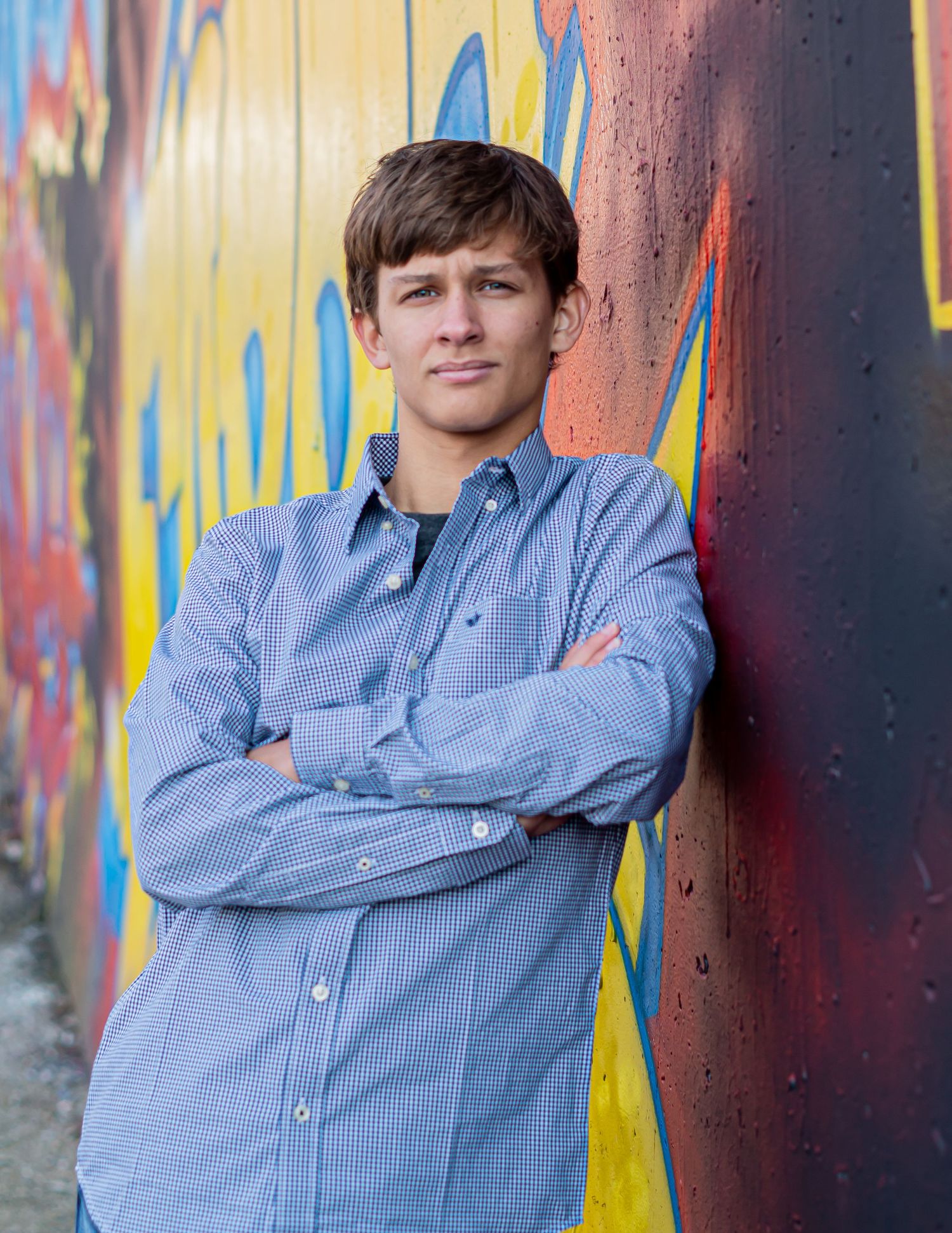 Portrait series against colorful graffiti wall wearing blue button-down shirt.