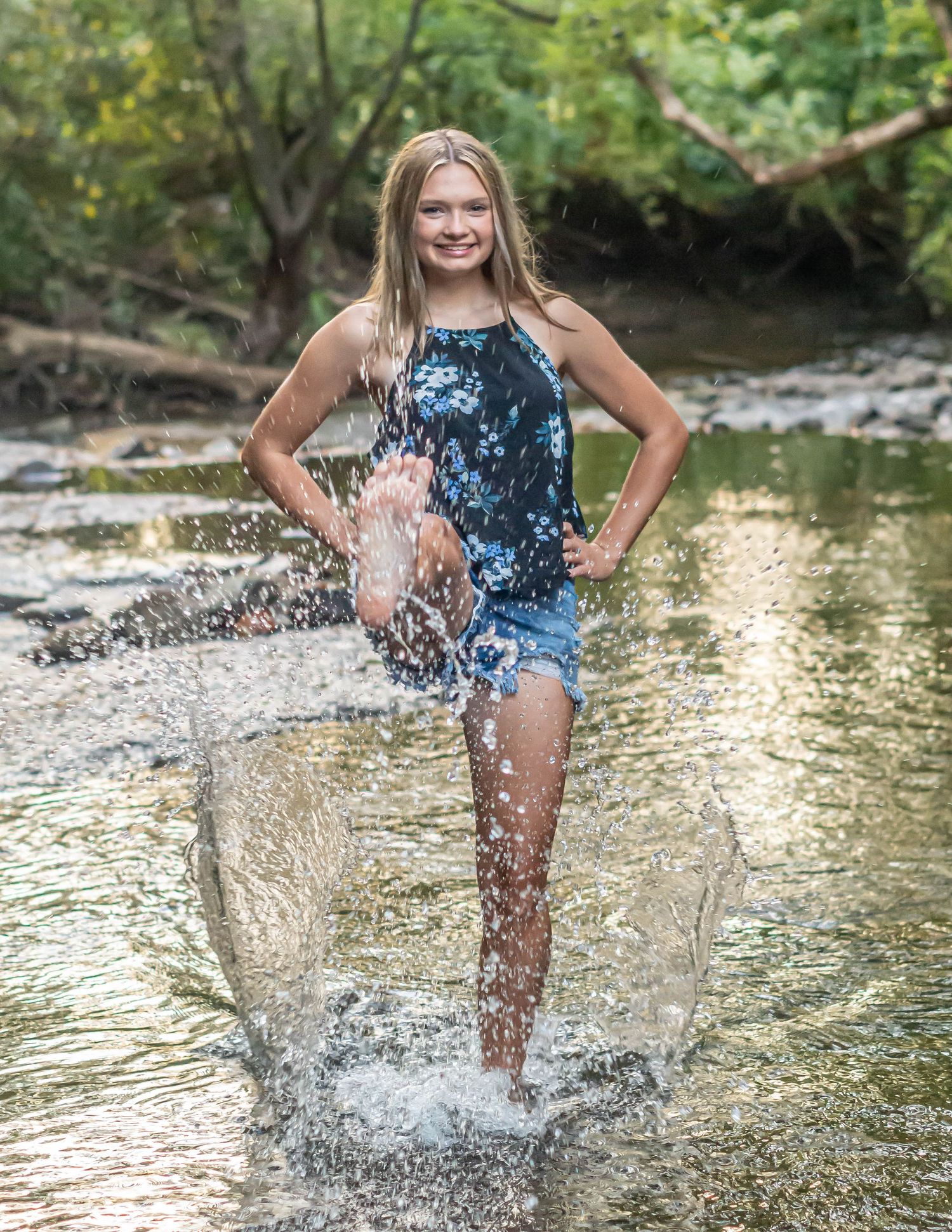 Playful portrait session splashing in creek wearing floral dress.