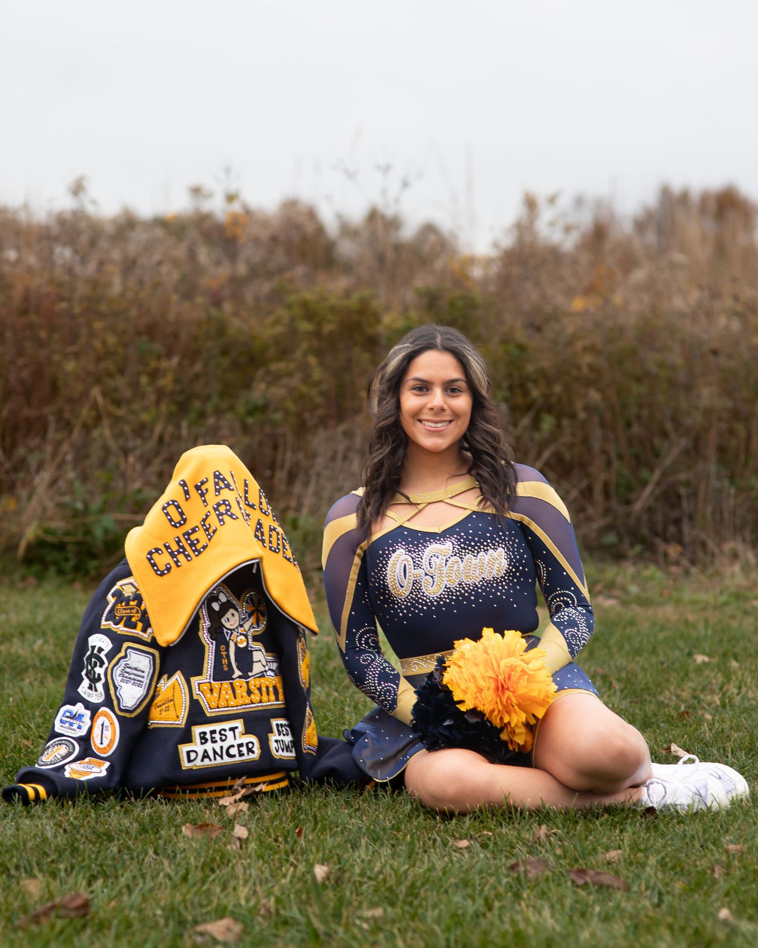 Cheerleader with pom poms and spirit wear displayed on grass field.