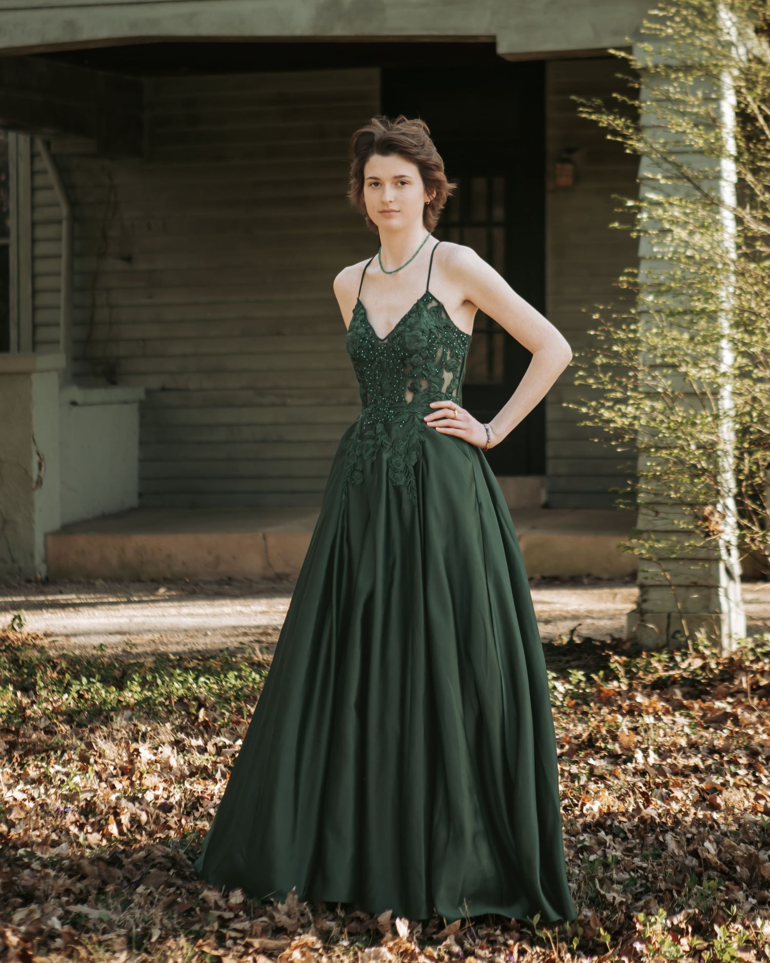 Elegant dark green dress flows gracefully during outdoor autumn photoshoot.