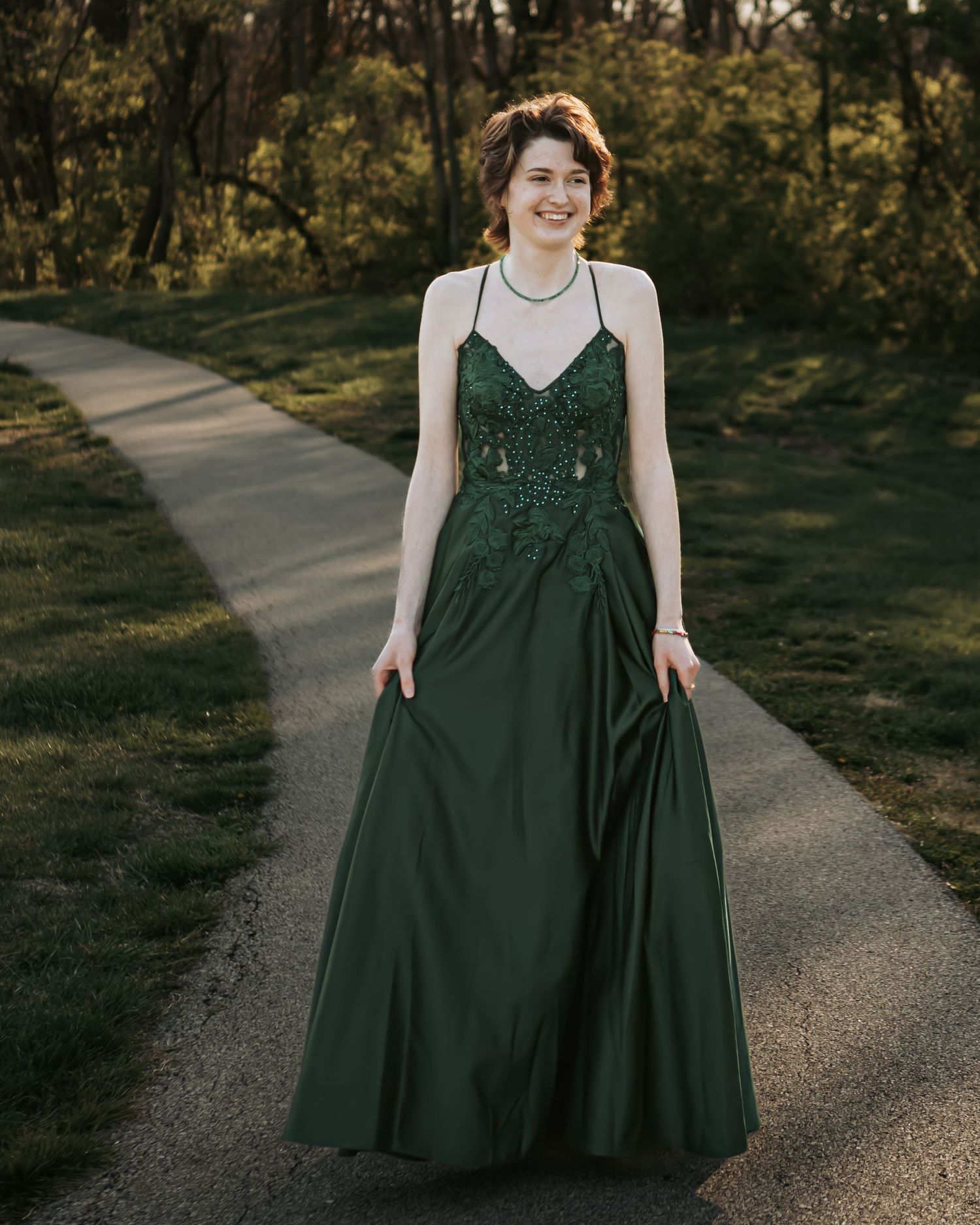 Spinning movement captured in dark green dress along sunlit outdoor path.