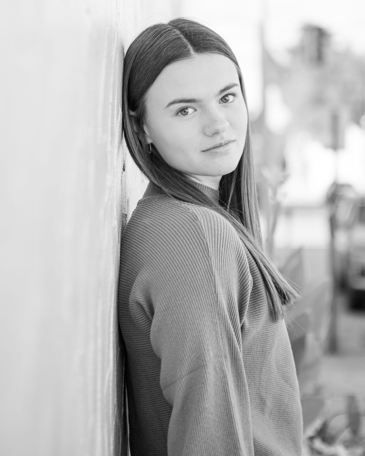 Black and white portrait with soft lighting against a white wall.