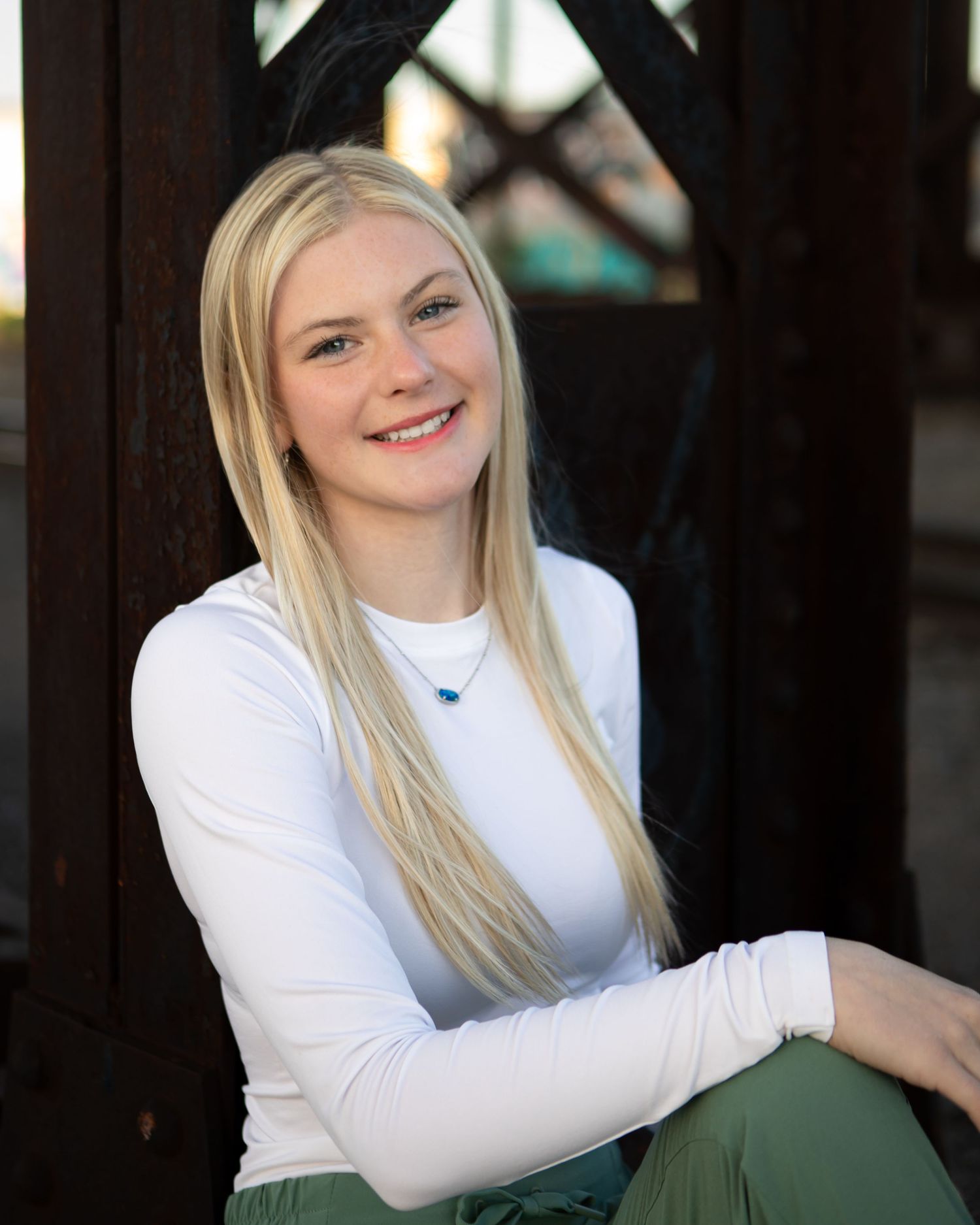 A white long-sleeve top paired with green pants in an outdoor setting.